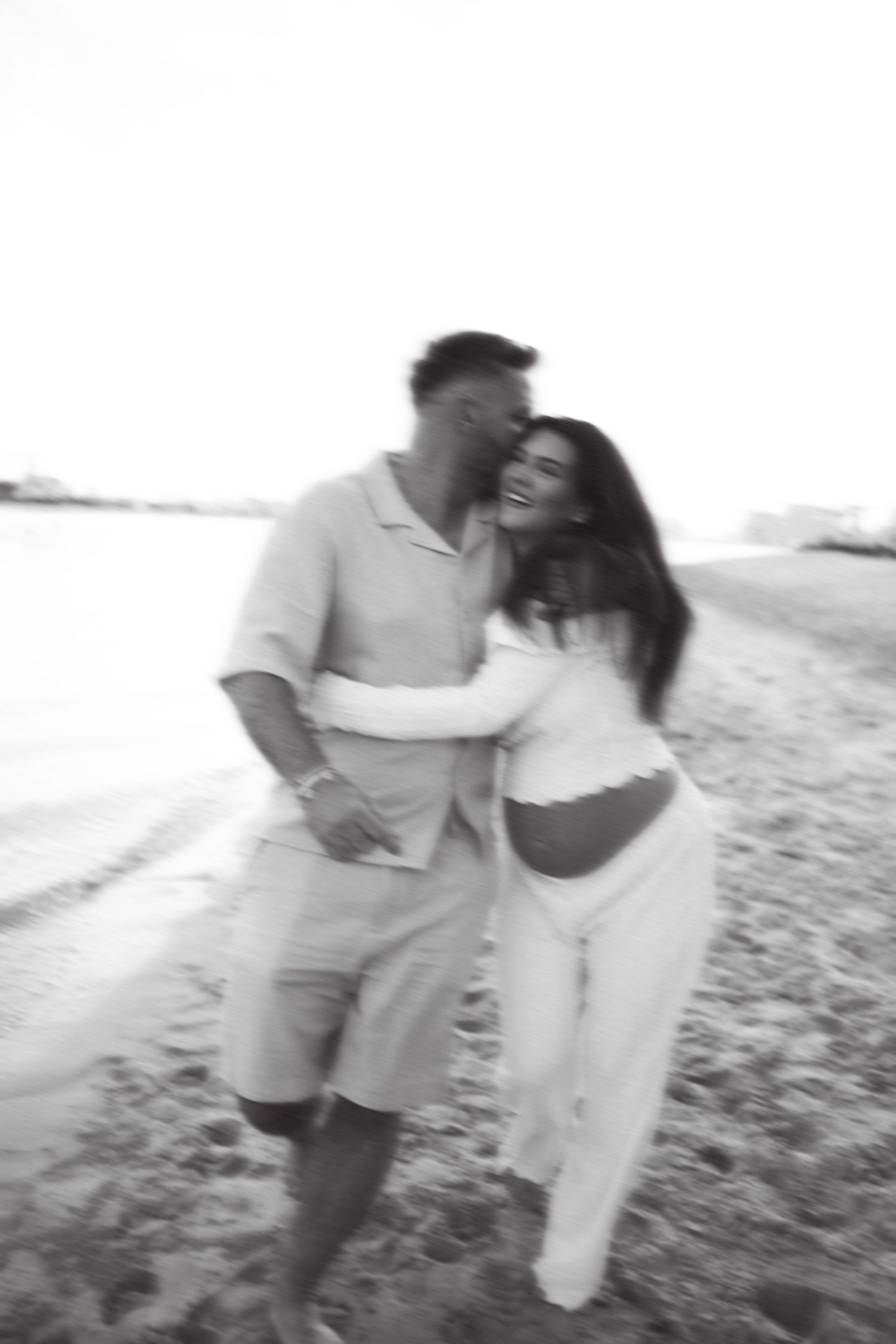 Blurred black and white photo of couple embracing on beach.
