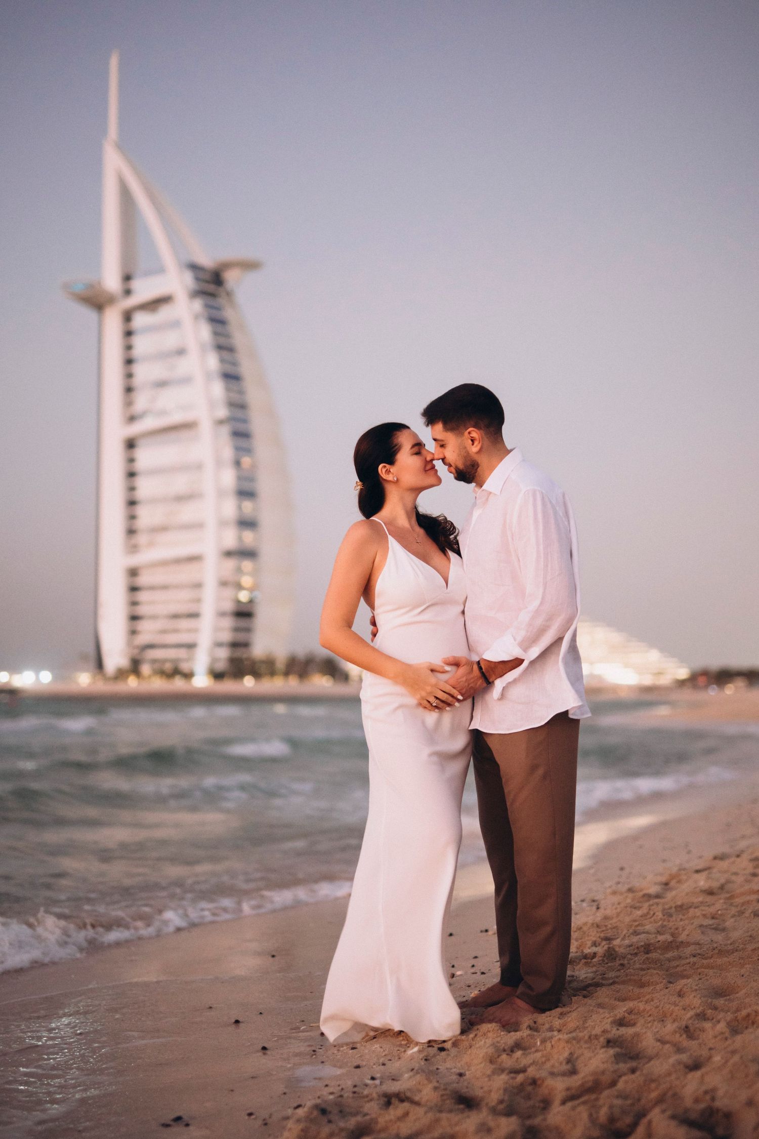 Romantic couple portrait on Dubai beach with Burj Al Arab hotel at sunset.