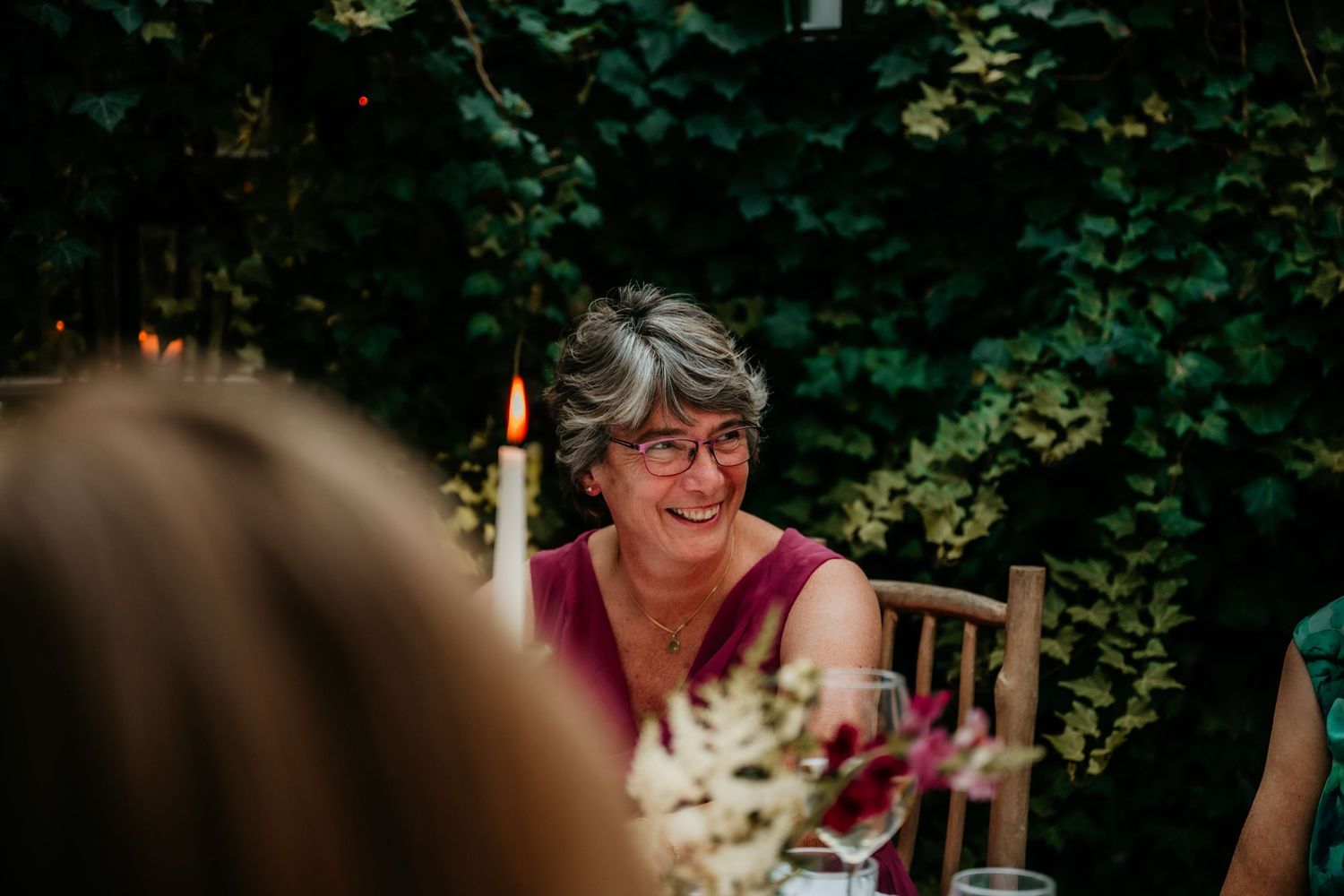 Wedding guests enjoying outdoor celebration among trees and greenery.