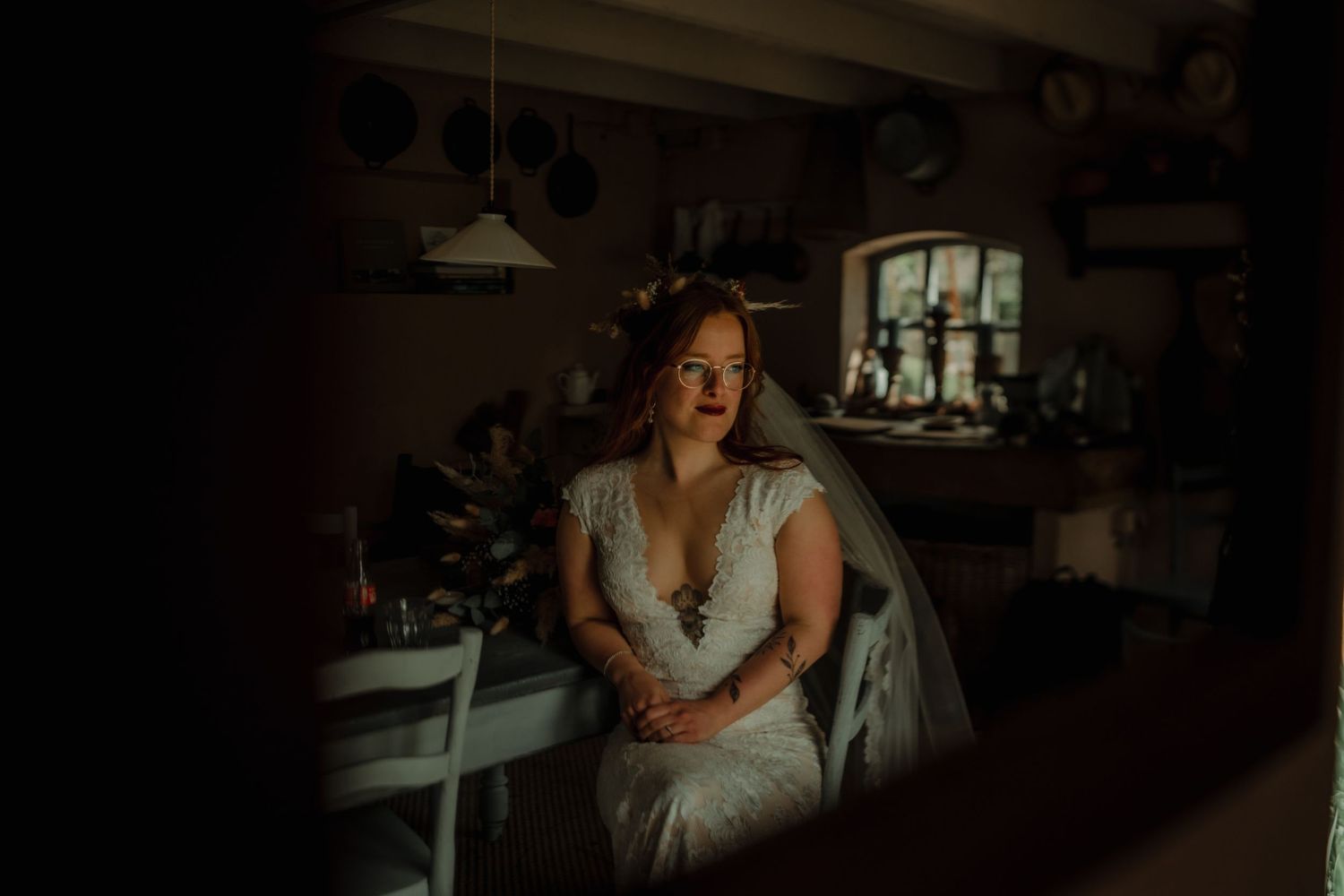 A person in a white dress poses in a dimly lit room with dramatic shadows and lighting.