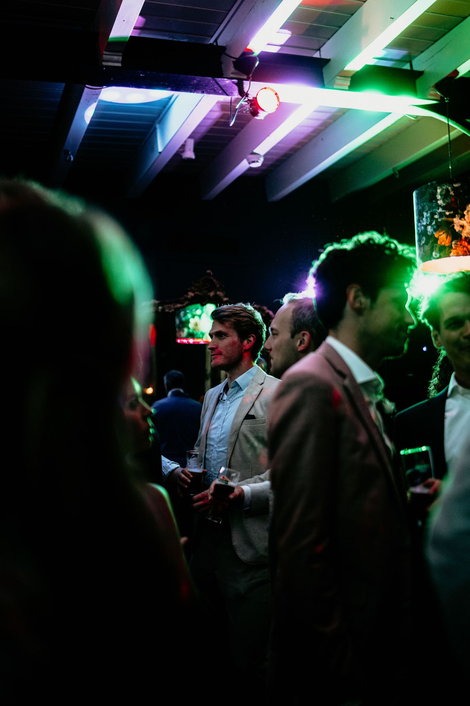 Wedding party dancing under colorful green and purple lighting effects.
