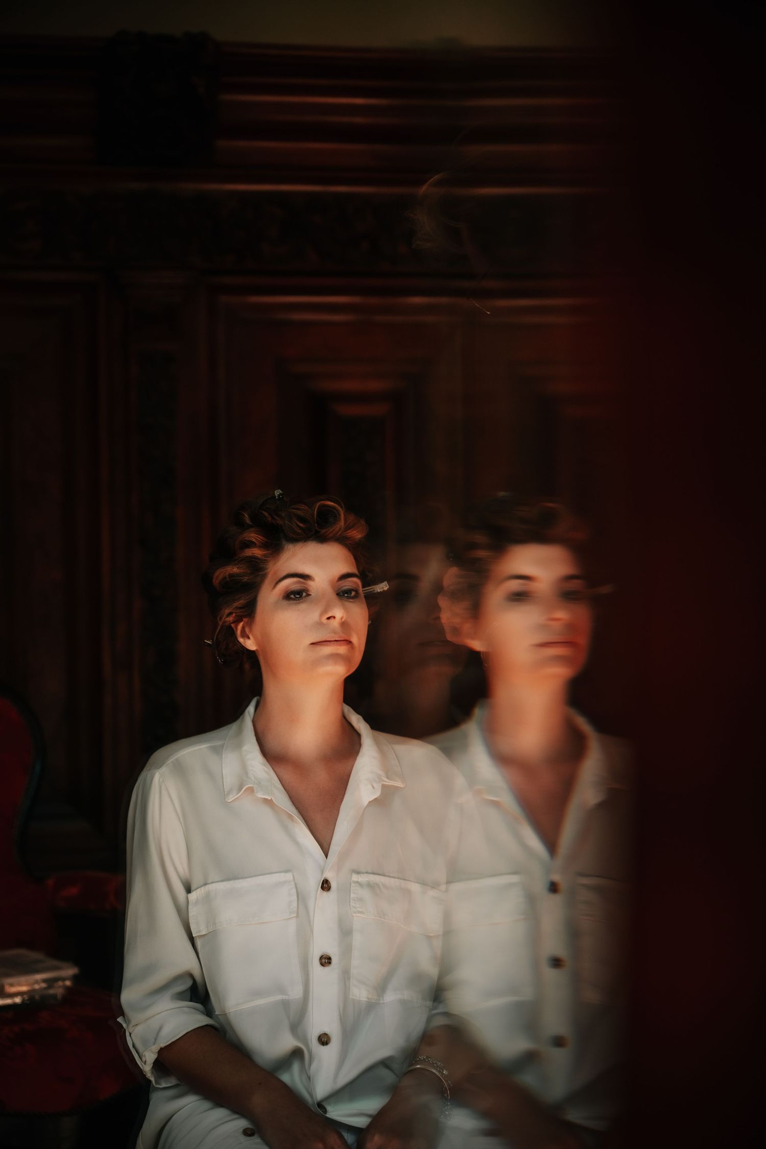 Artistic portrait in dramatic lighting showing a white button-up shirt against a dark background.