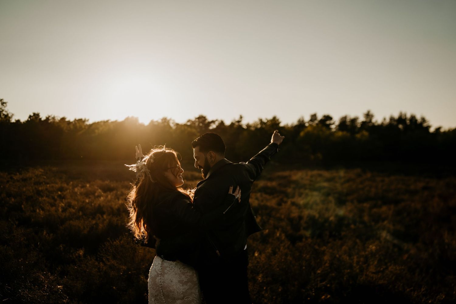 Golden sunlight illuminates silhouettes of people gathered in a field at dusk.