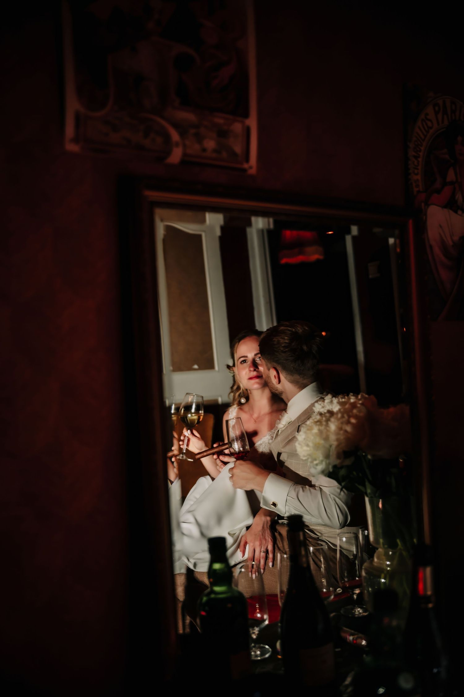 Couple sharing a romantic moment with champagne glasses in a dimly lit, intimate restaurant setting.