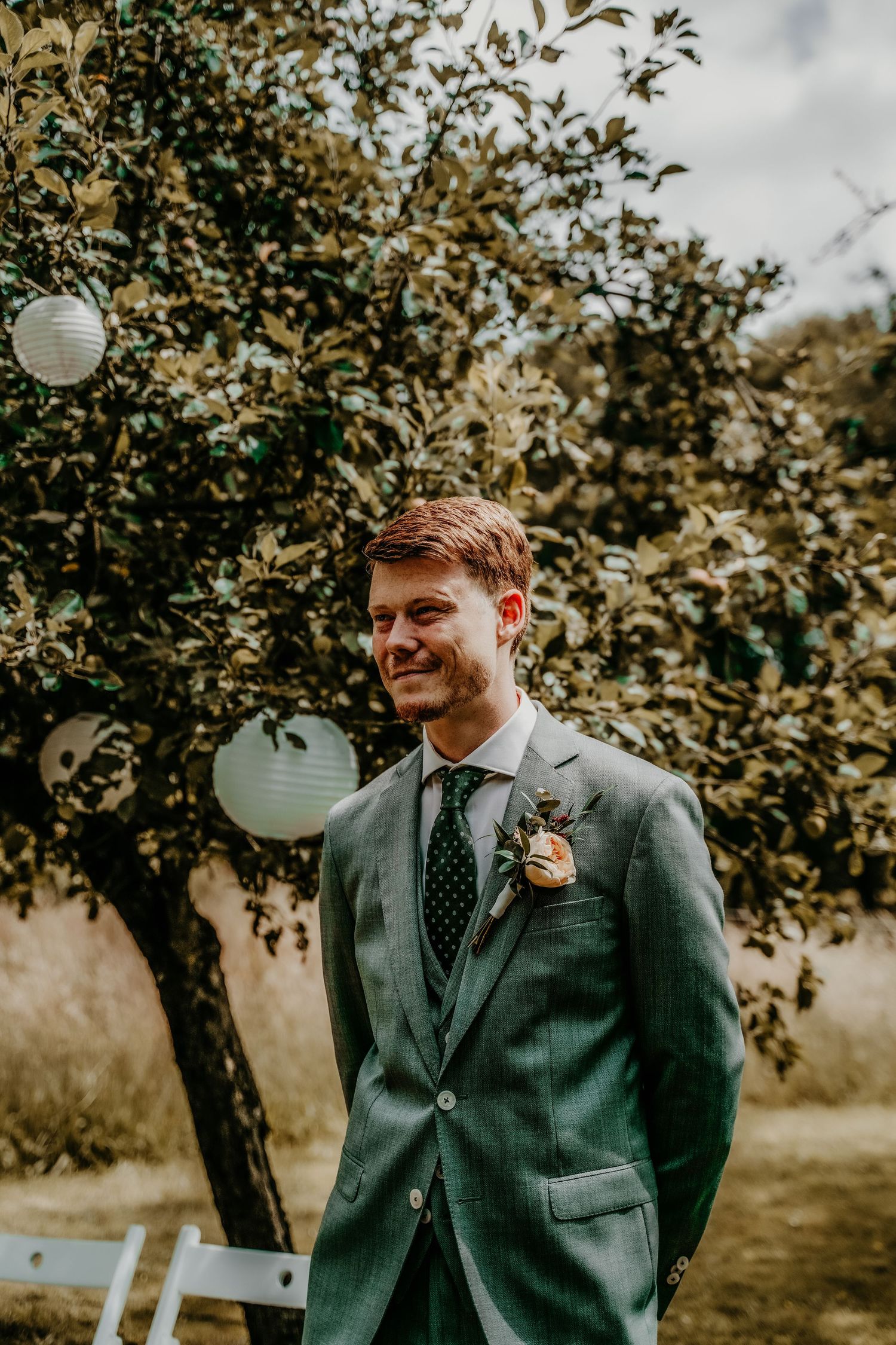 Outdoor garden wedding scene with paper lanterns and greenery.