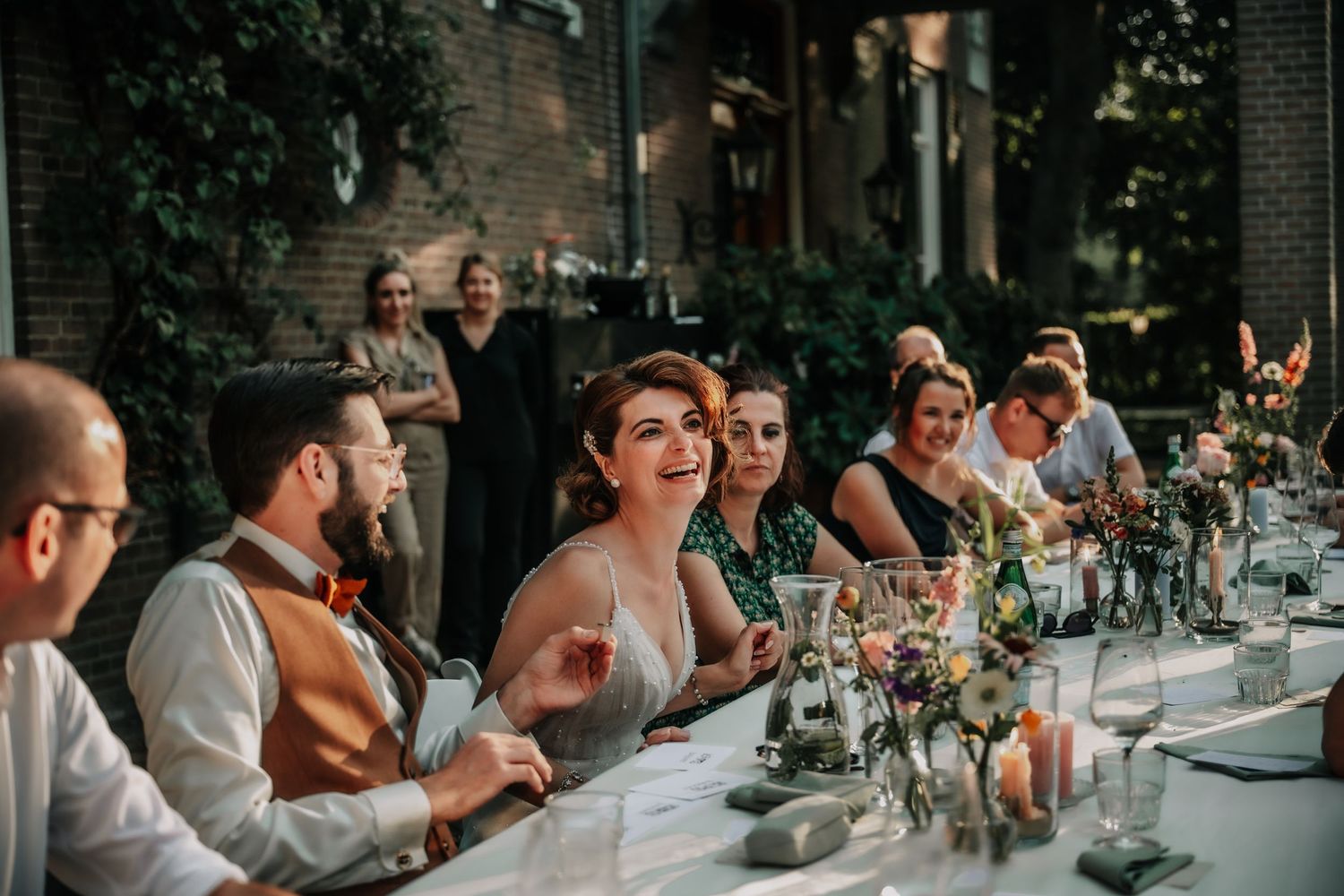 Long outdoor dining table set up for a wedding reception under string lights.