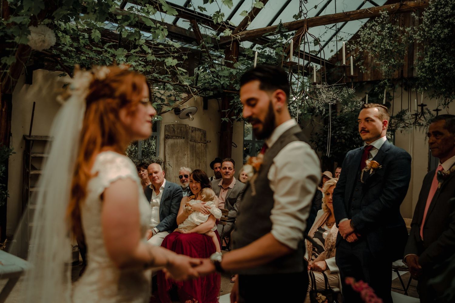 Outdoor wedding ceremony in progress with guests seated in a garden setting.