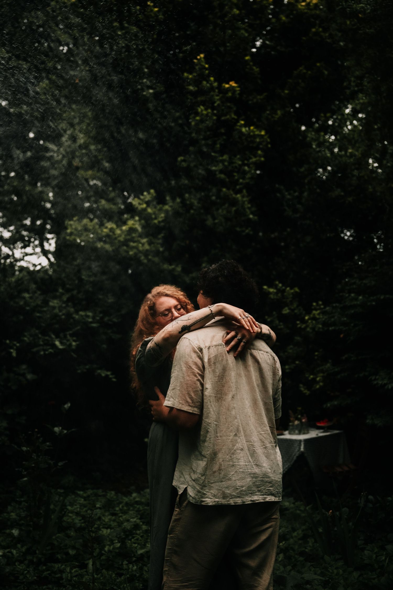 A series of dark, moody photos show someone in white clothing against a shadowy forest backdrop.