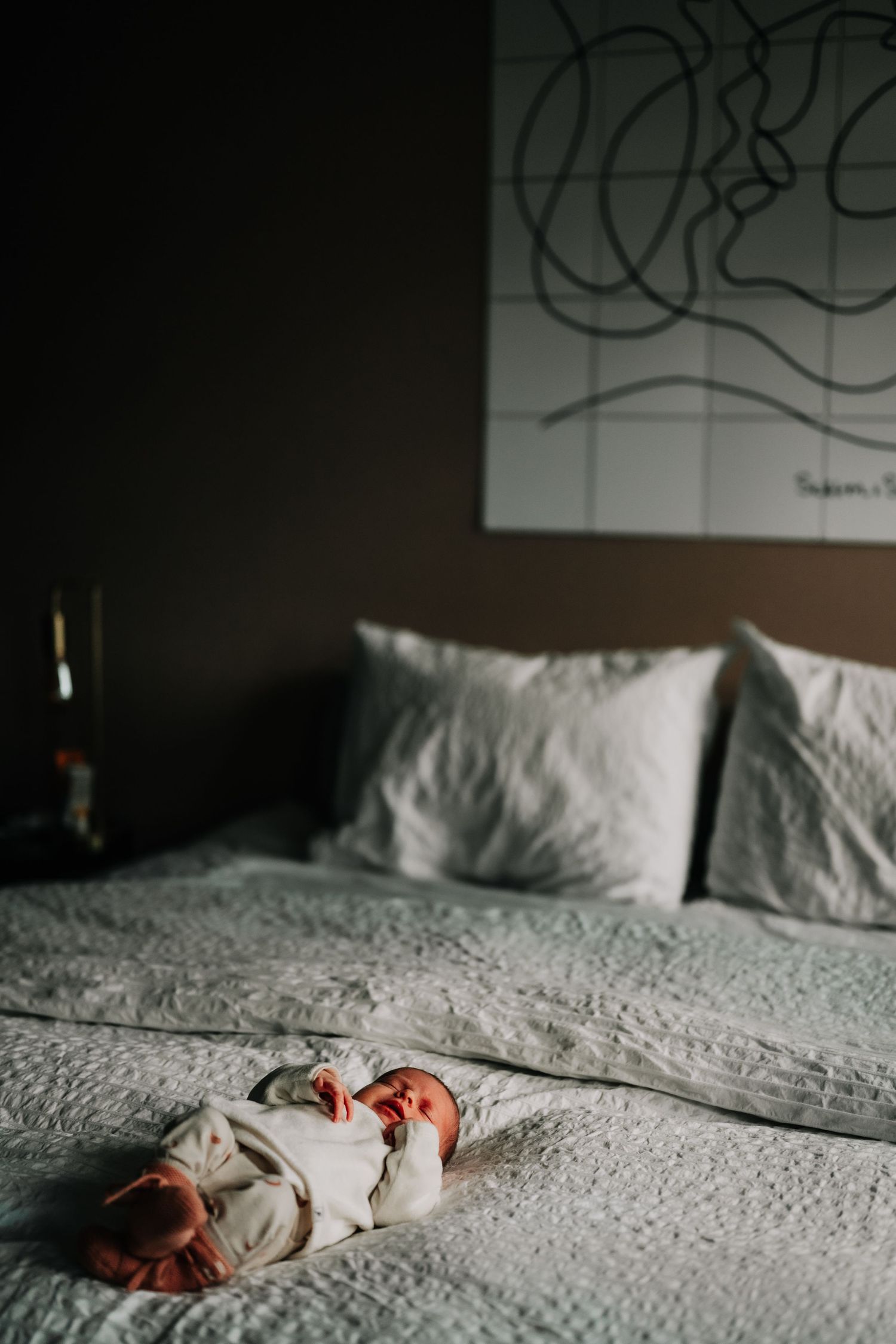 A sleeping newborn rests peacefully on white bedding.