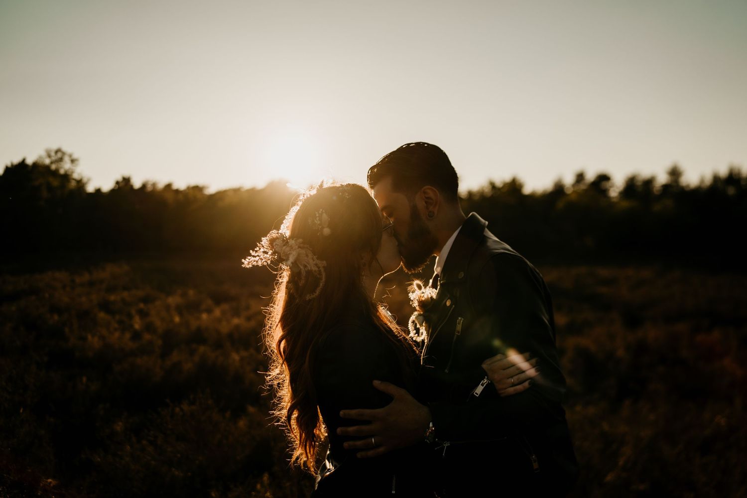 Silhouetted couple shares intimate moment against dramatic sunset sky.
