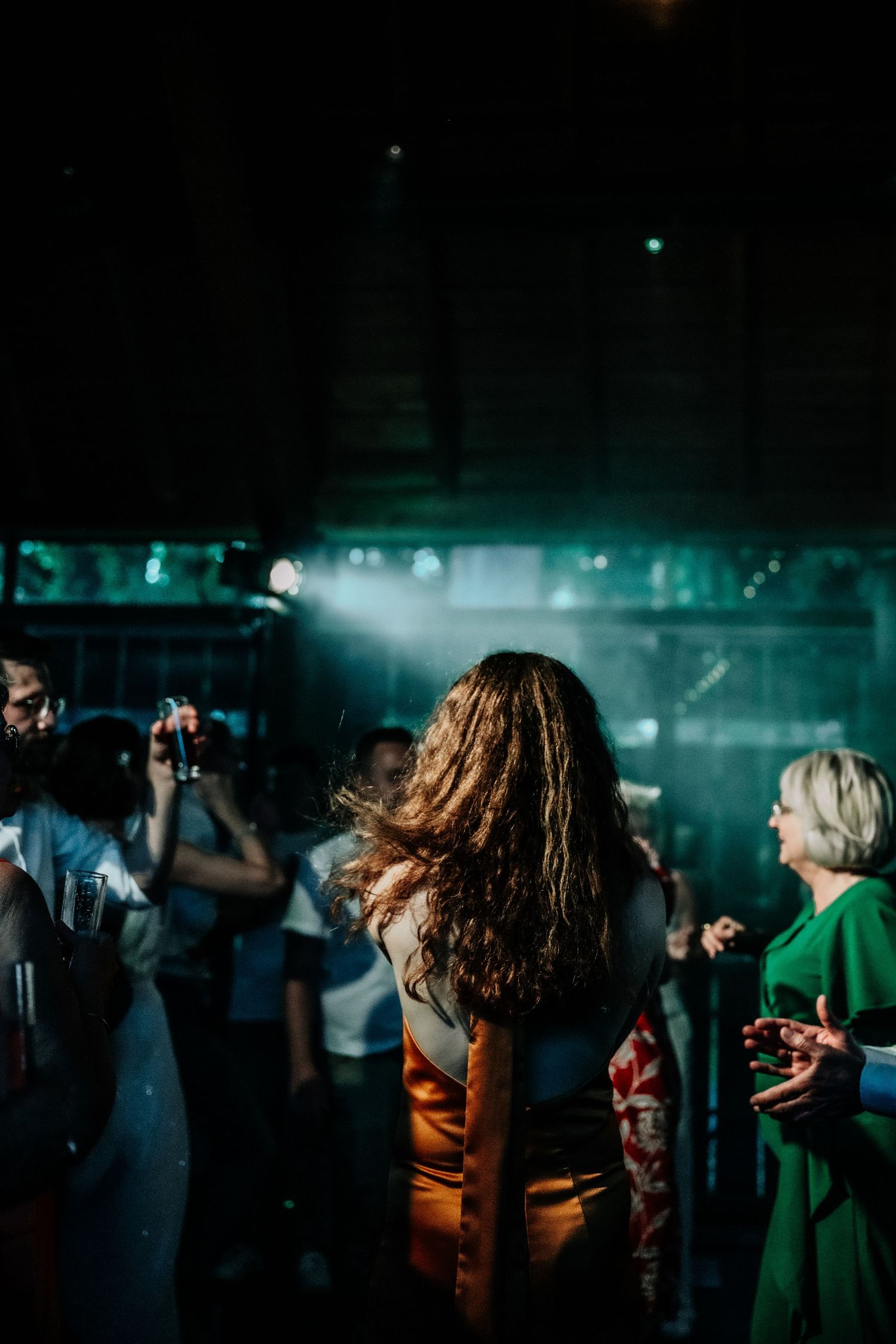 People dancing at a nightclub with atmospheric green lighting and fog effects.