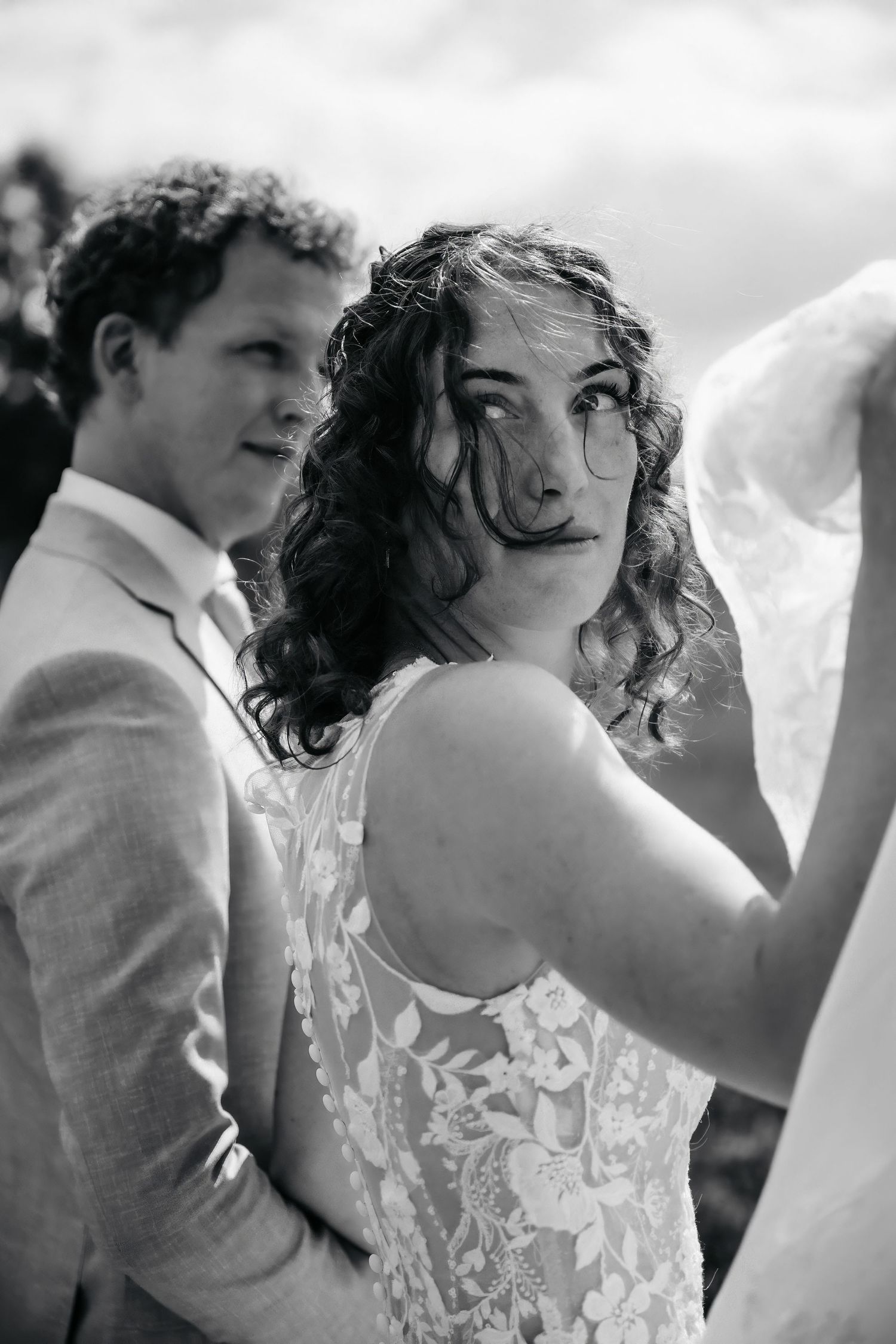 A black and white portrait captures a tender moment between newlyweds outdoors.