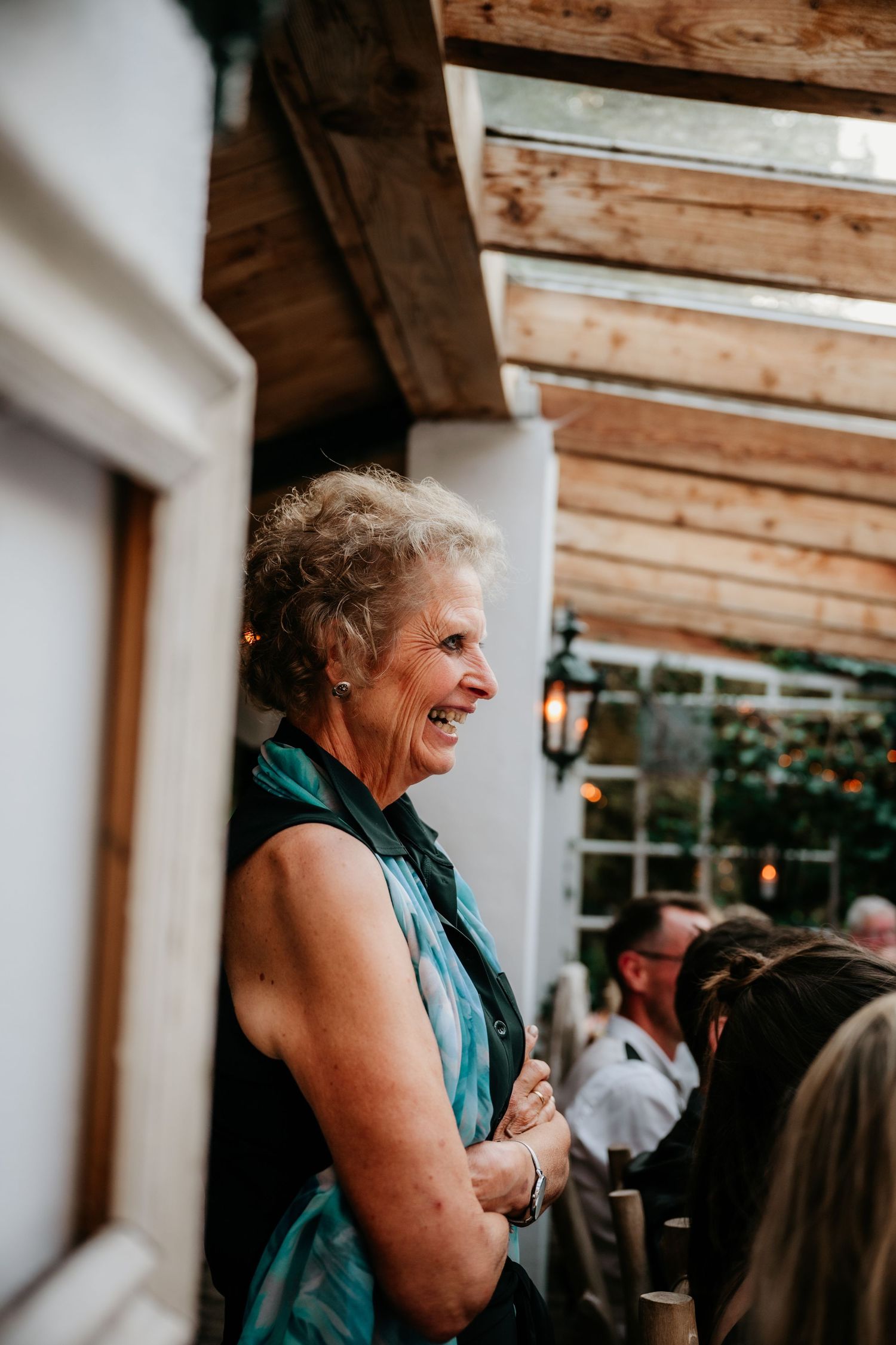 Wedding guest enjoying reception festivities under wooden pergola.