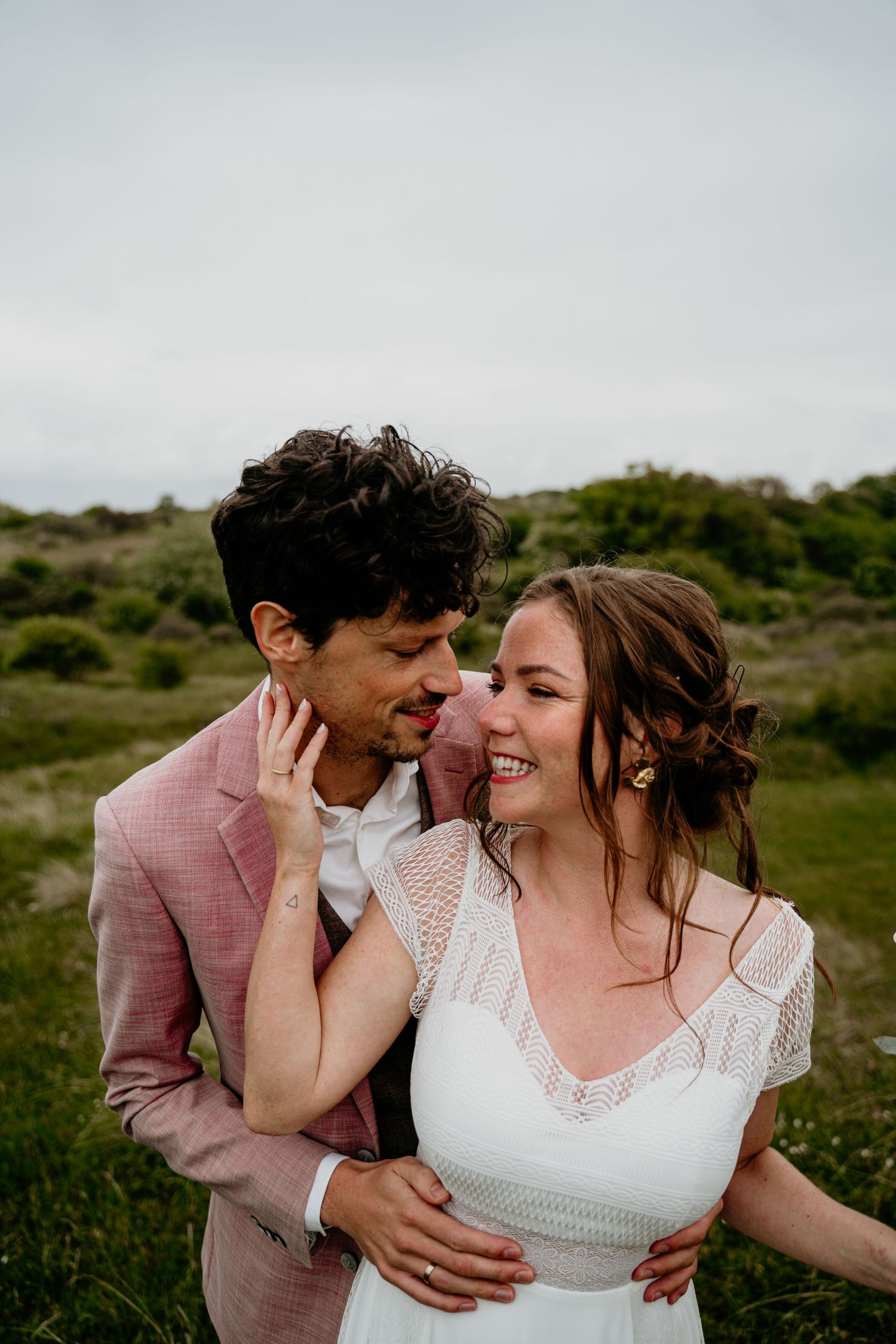 Couple shares intimate moments and laughter in an outdoor field setting.
