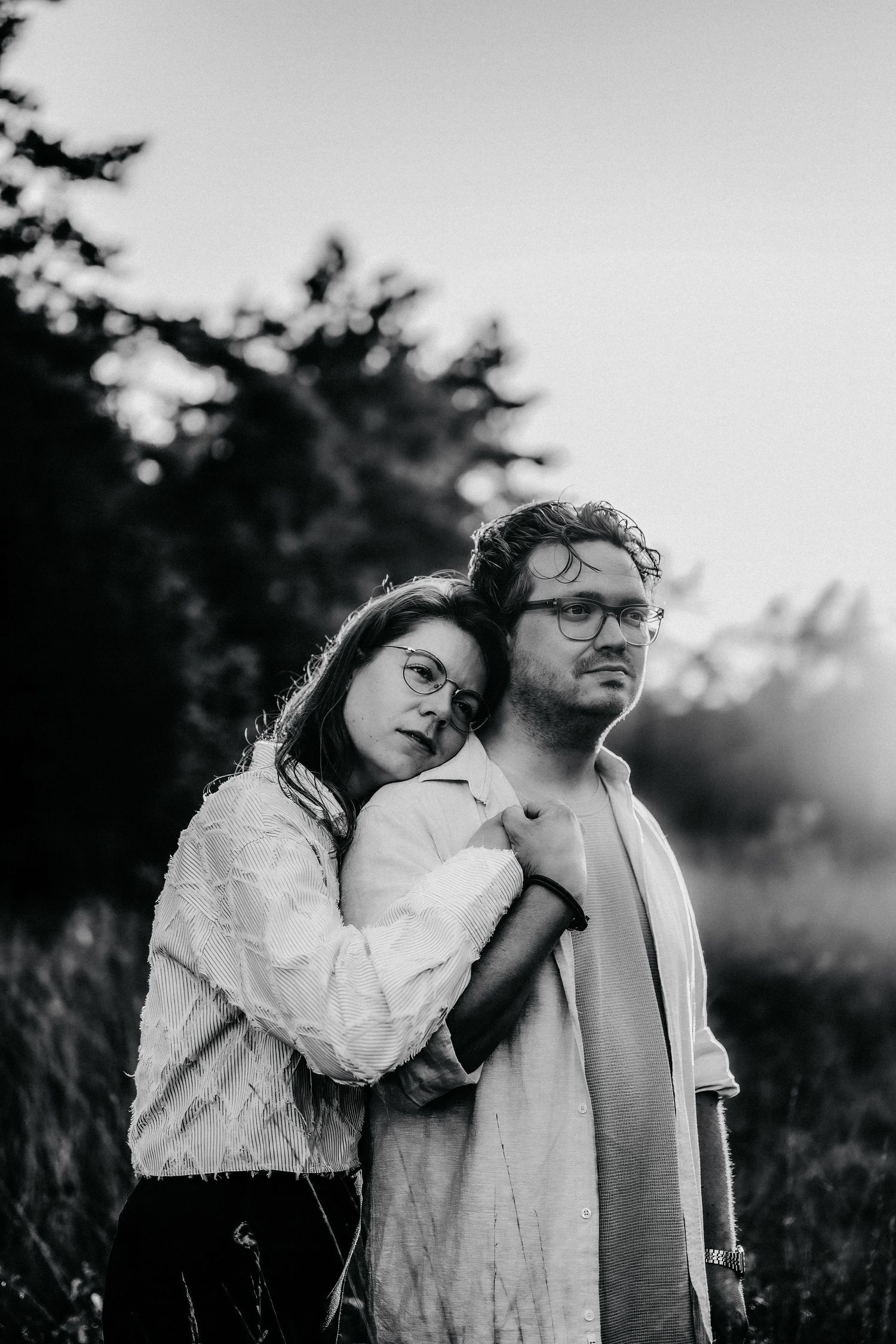 A romantic black and white sequence of a couple embracing outdoors against natural foliage at sunset.