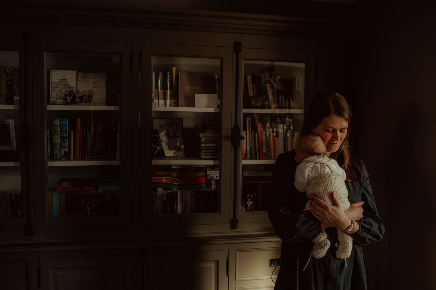 Dark wooden bookshelves provide a backdrop for a gentle nurturing scene.