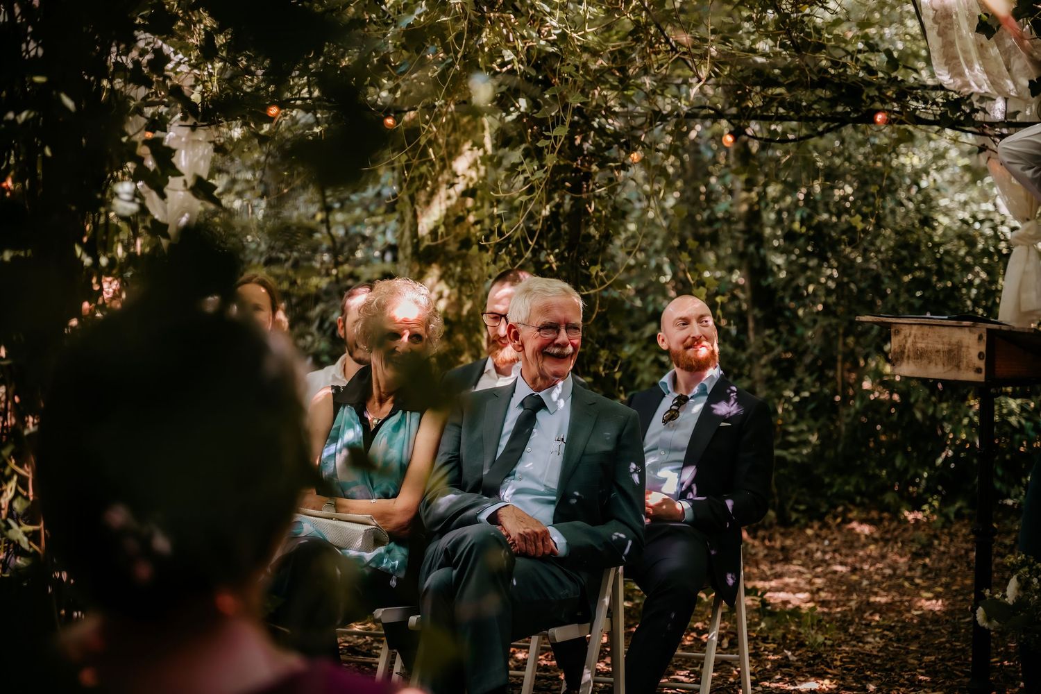 Outdoor wedding reception with guests mingling under autumn trees.