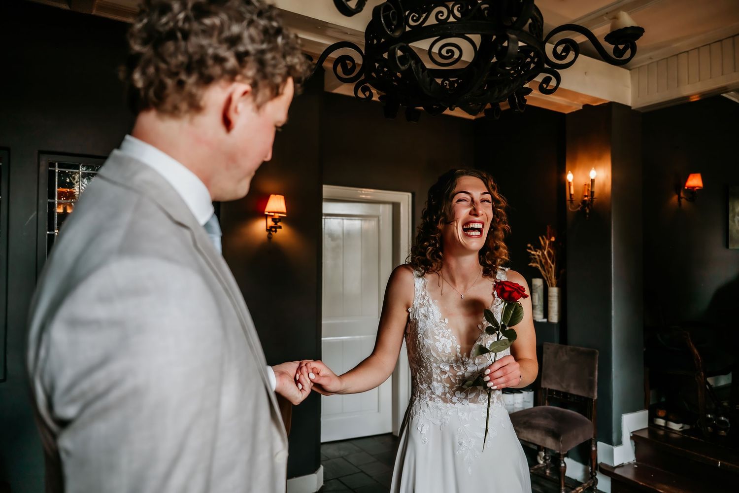 Joyful couple shares intimate moments during indoor wedding celebration with ornate decor and warm lighting.