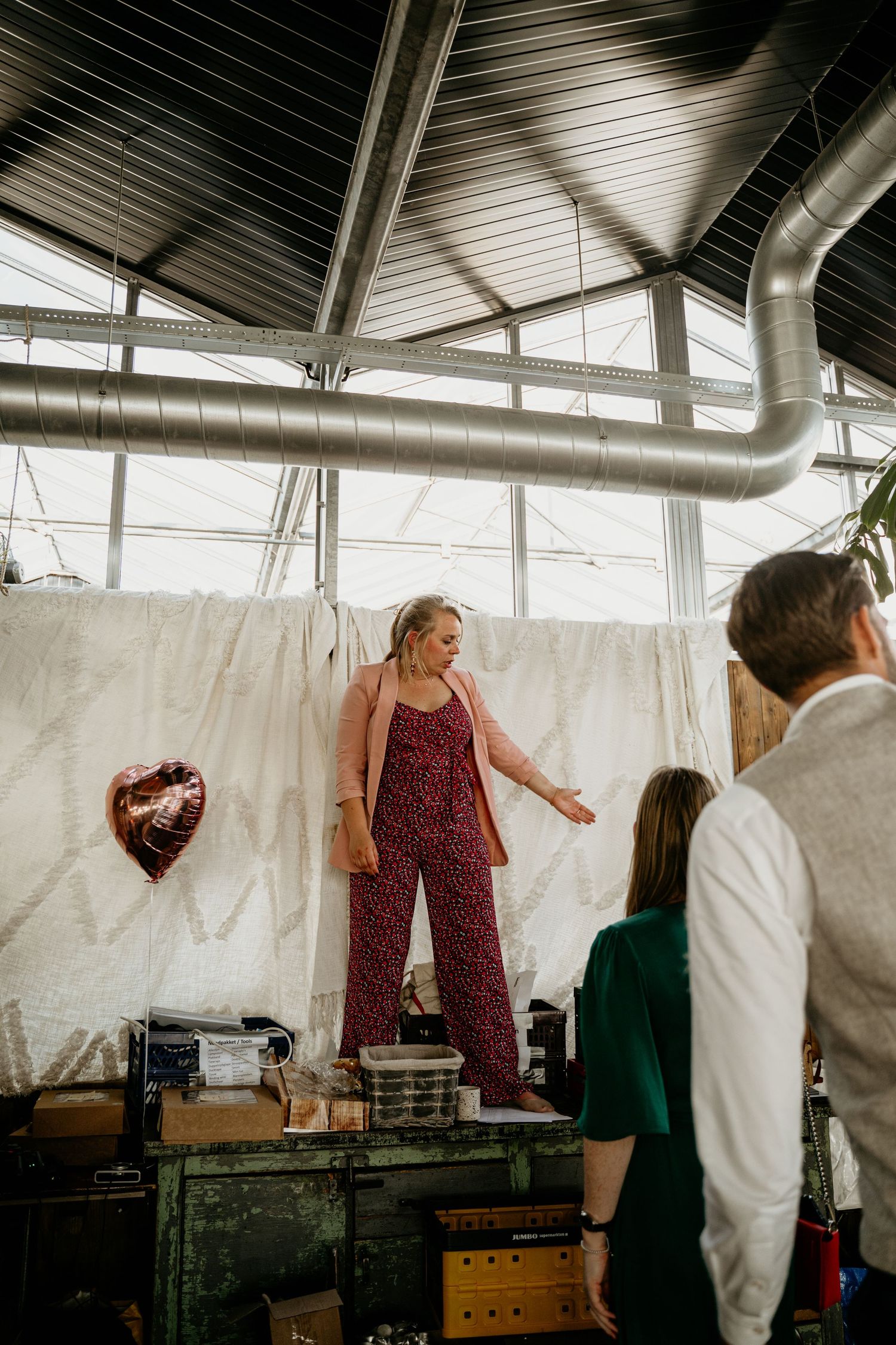 A festive indoor gathering with people celebrating under industrial ductwork and white draping.