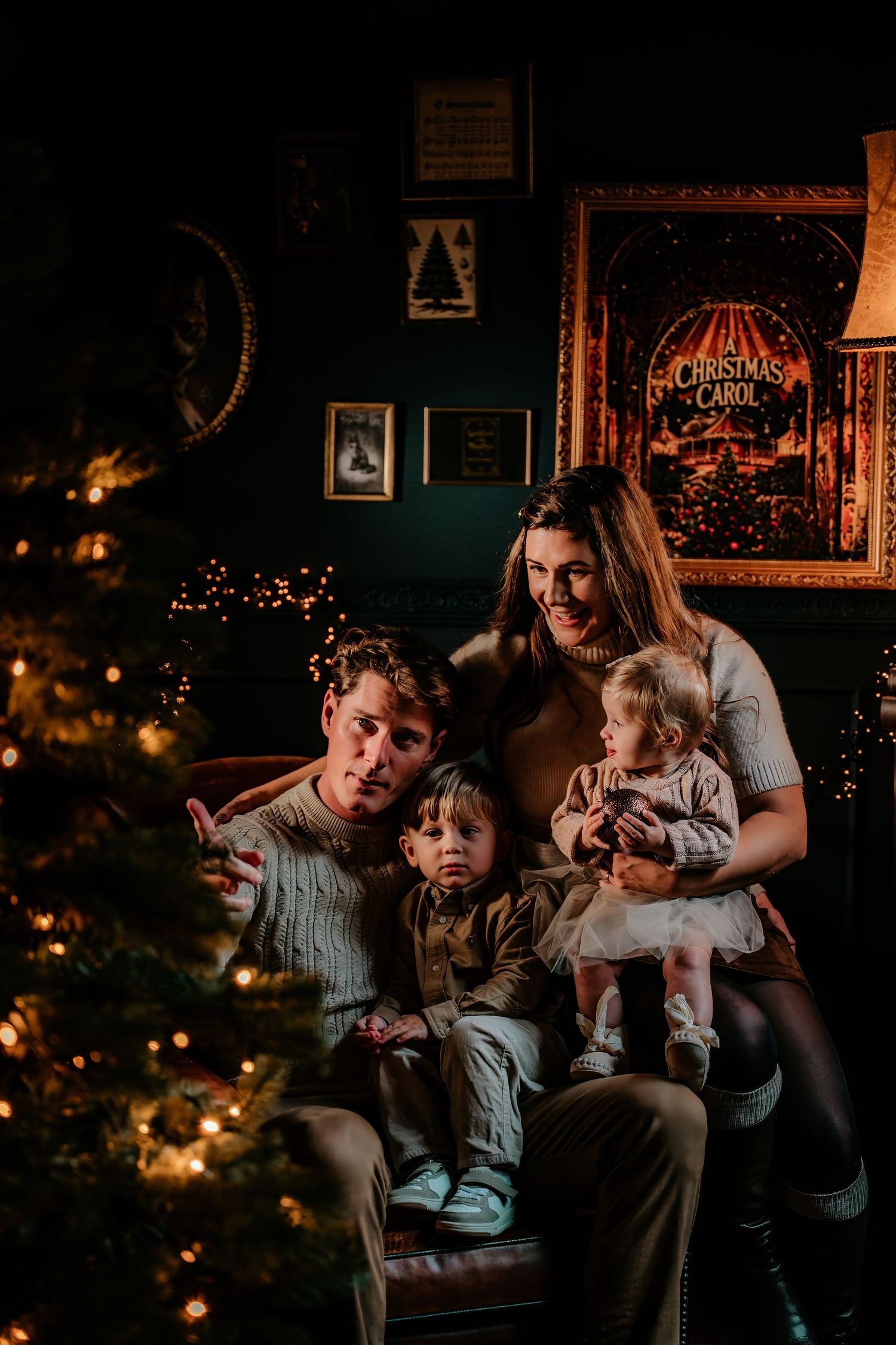 A dimly lit room with a Christmas tree and cozy seating area creates a warm holiday atmosphere.