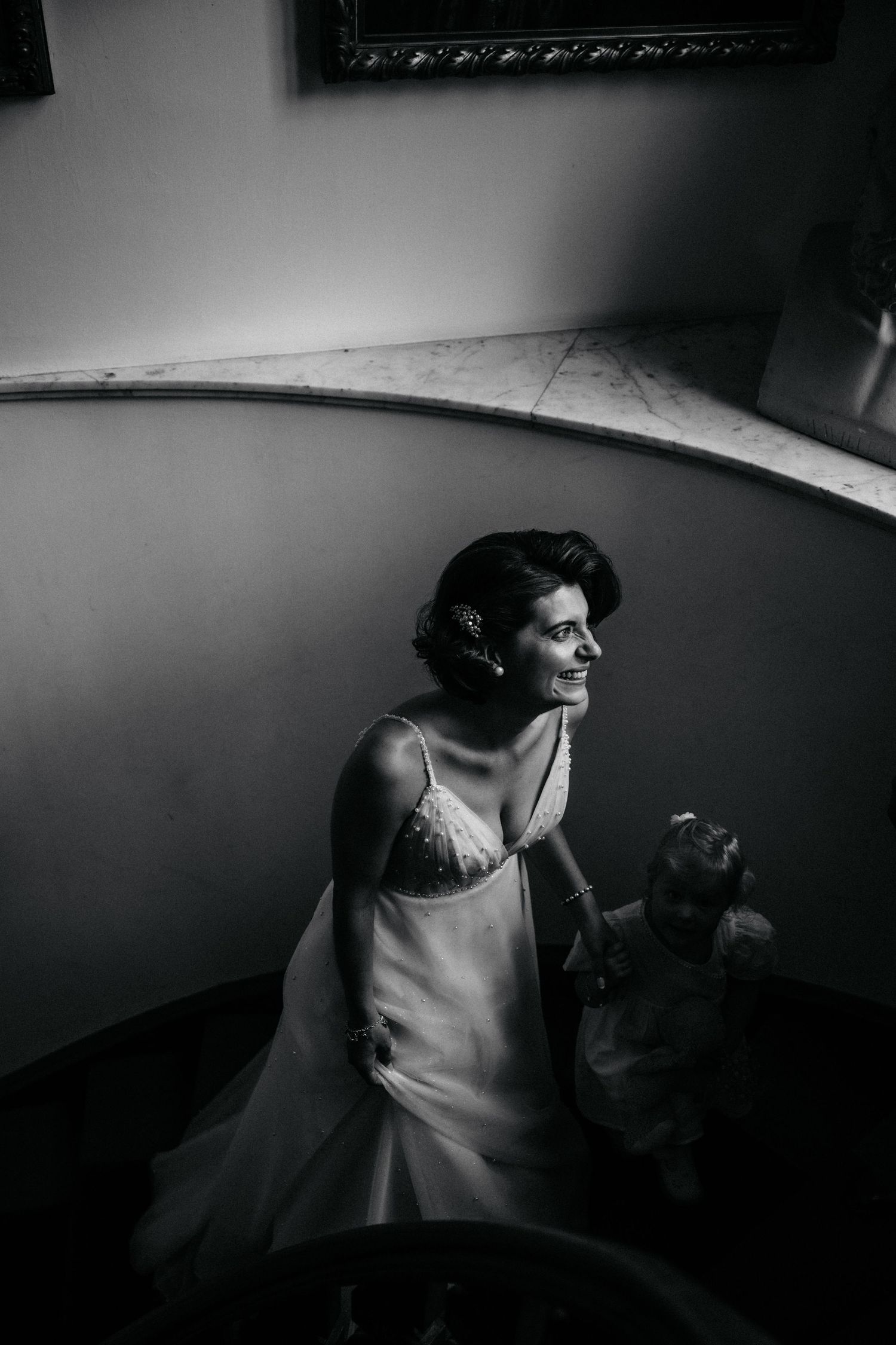 Dramatic black and white portrait in moody lighting against curved wall.
