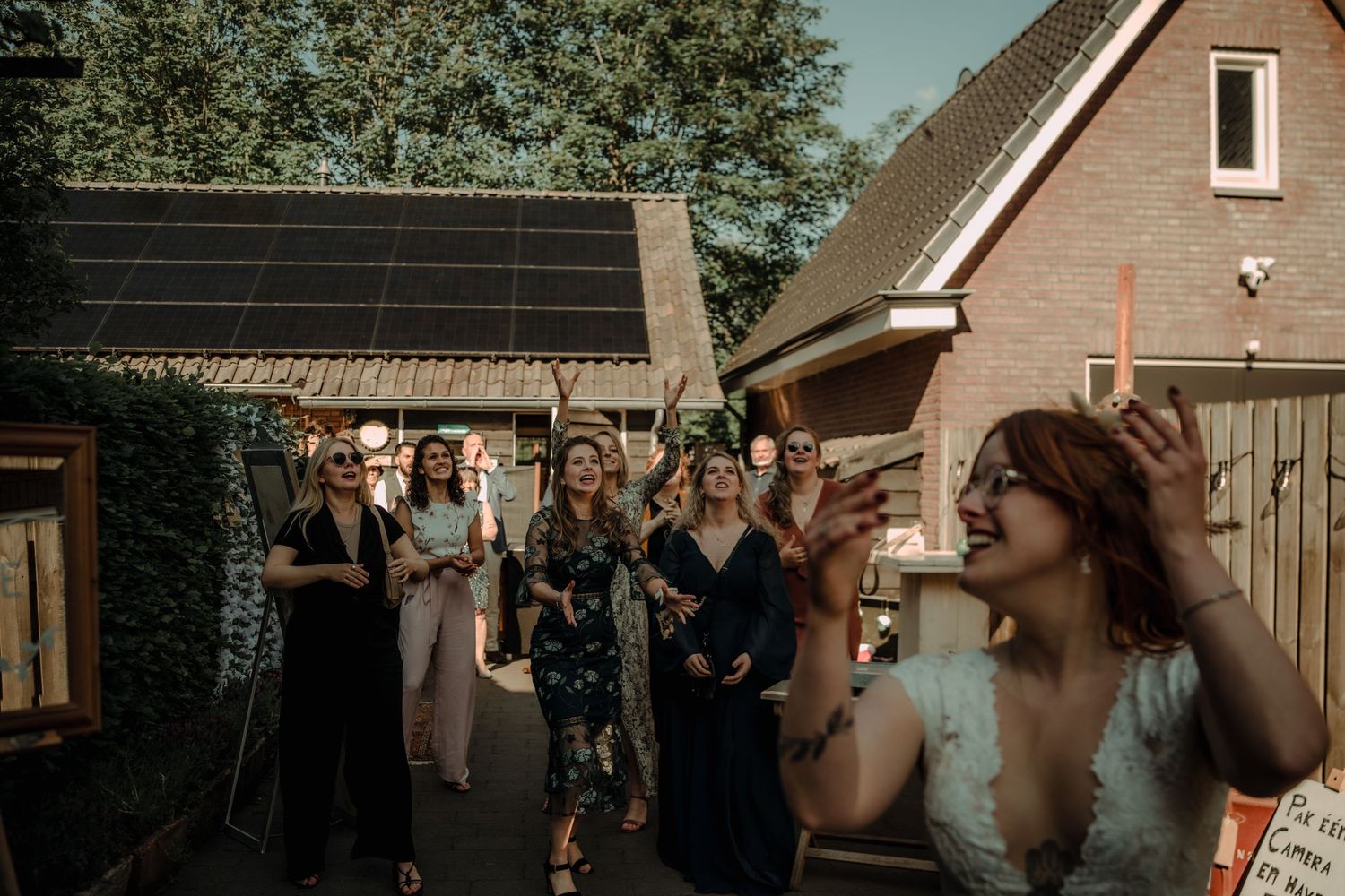 Wedding party celebrates outdoors at sunset with champagne toasts and laughter.