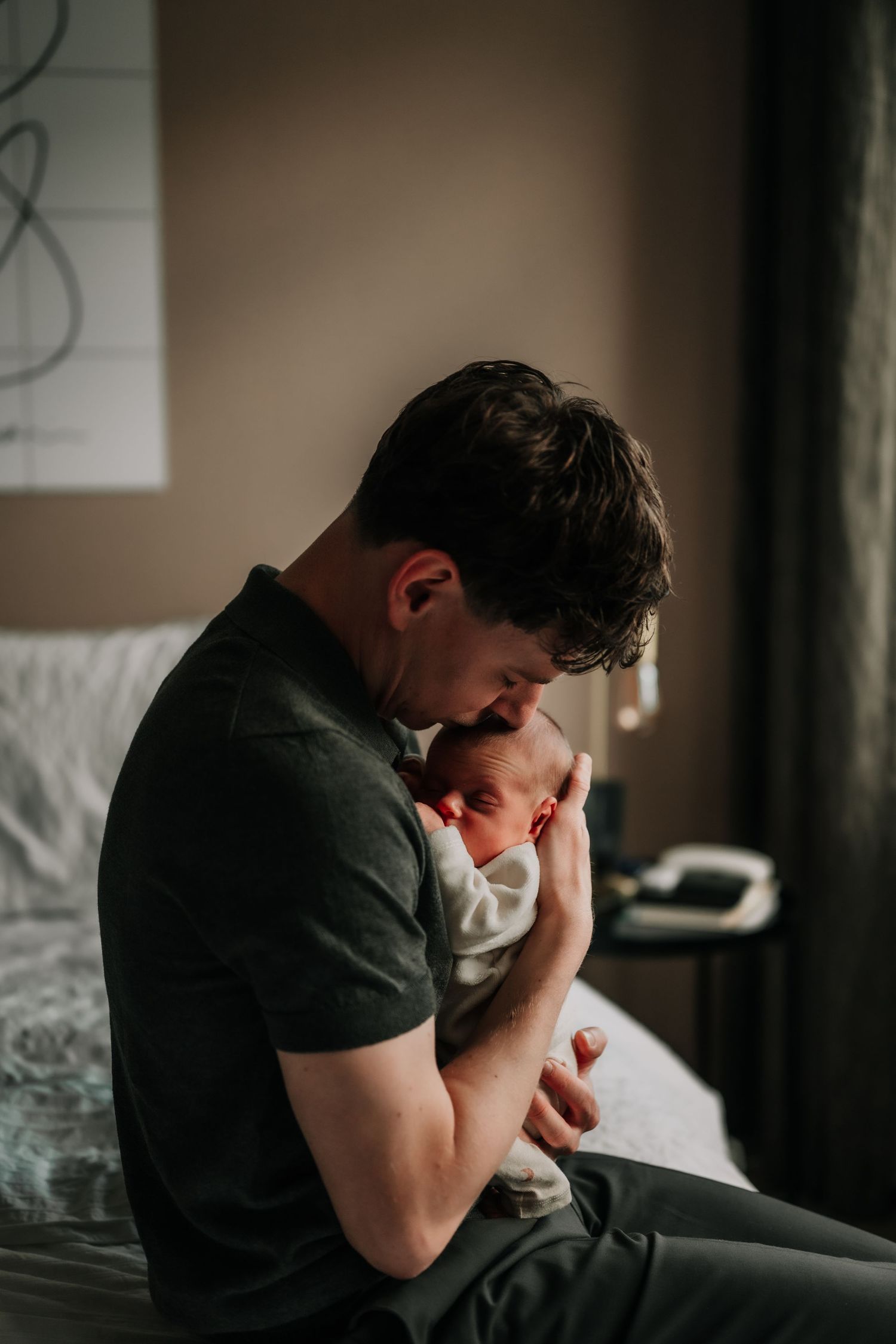 An intimate moment with a newborn against a dark backdrop.