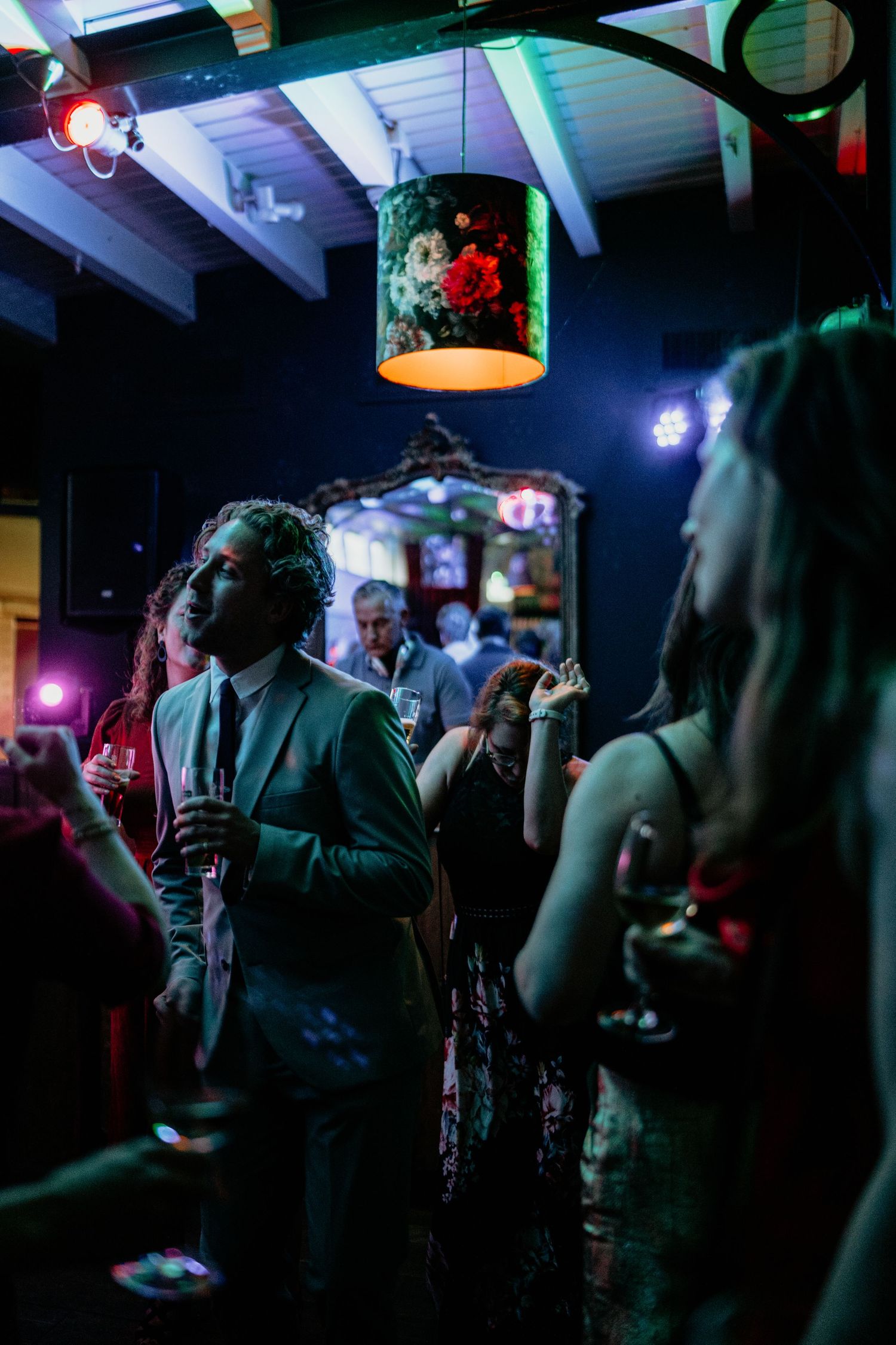 Dark nightclub scene with colorful stage lighting and dancing crowd silhouettes.