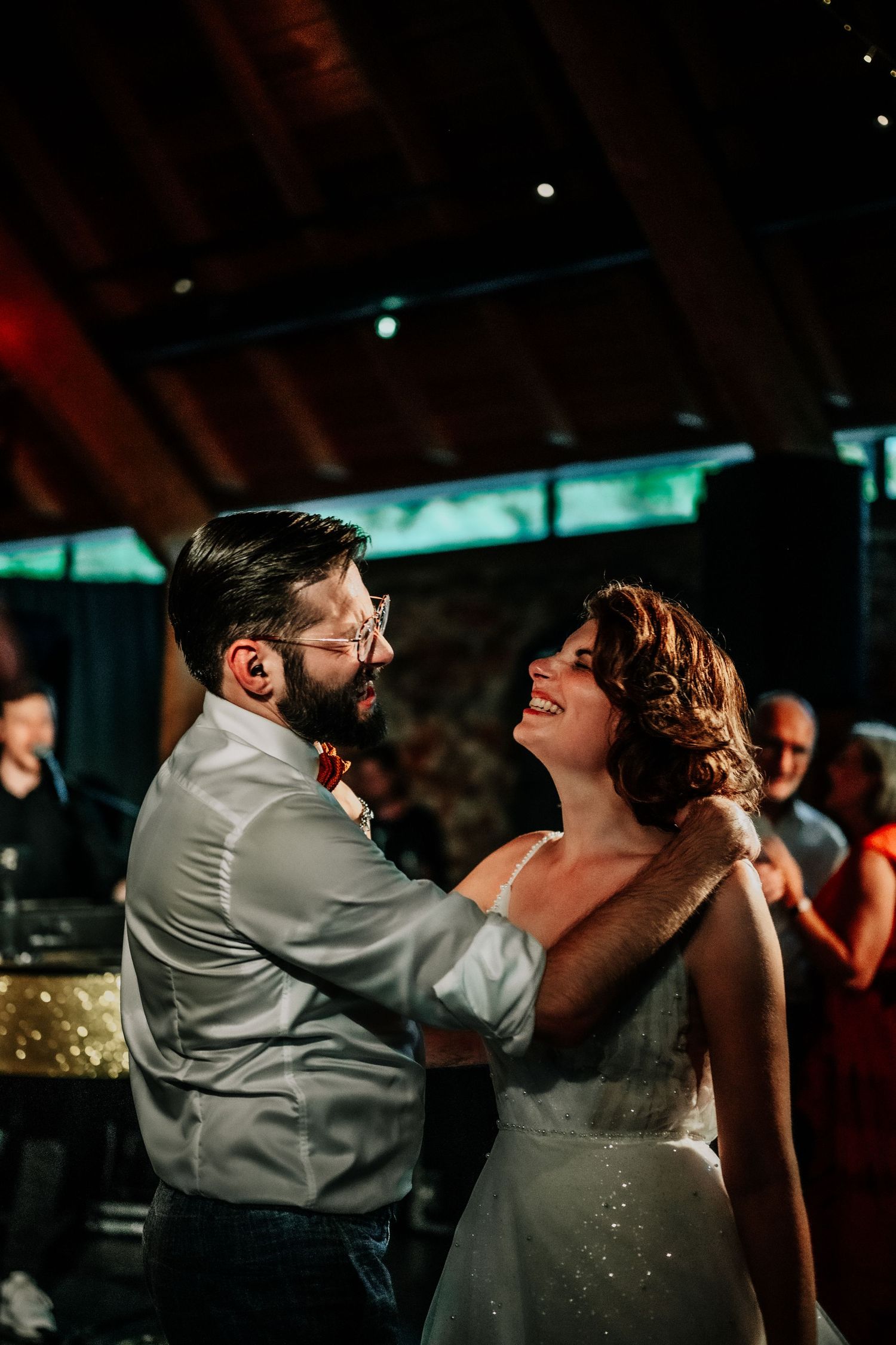 Couple dancing together under dramatic lighting at an indoor reception.