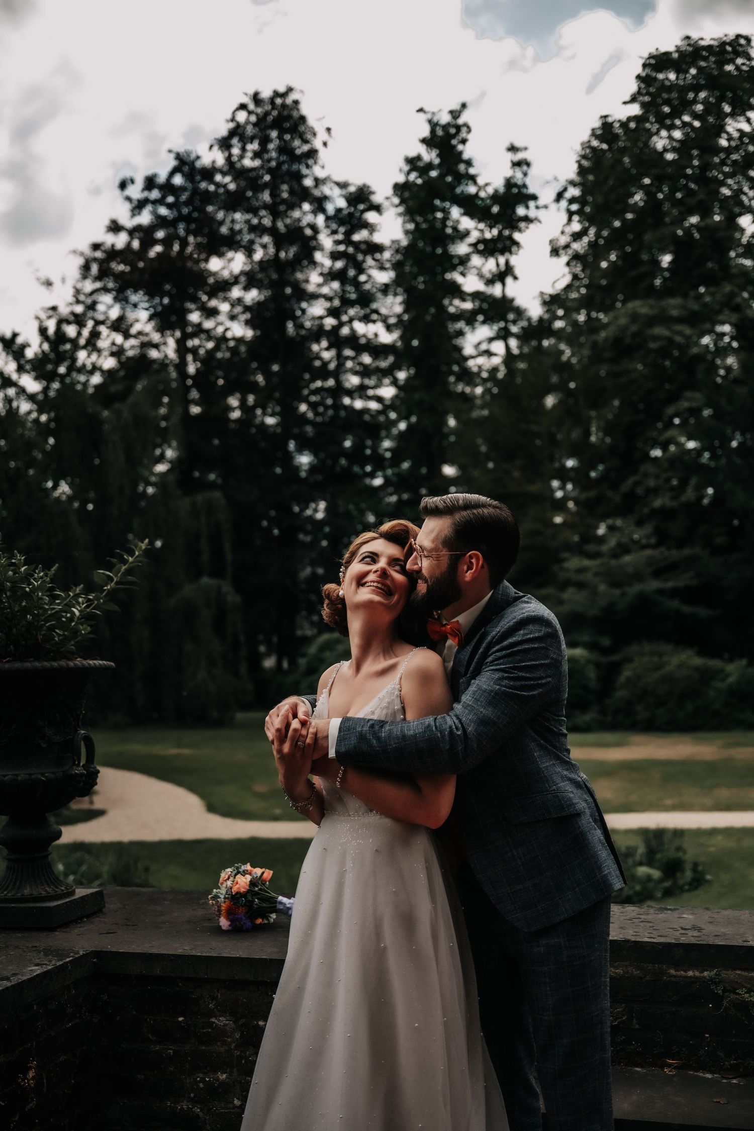 A romantic wedding moment captured outdoors with tall trees creating a natural backdrop.