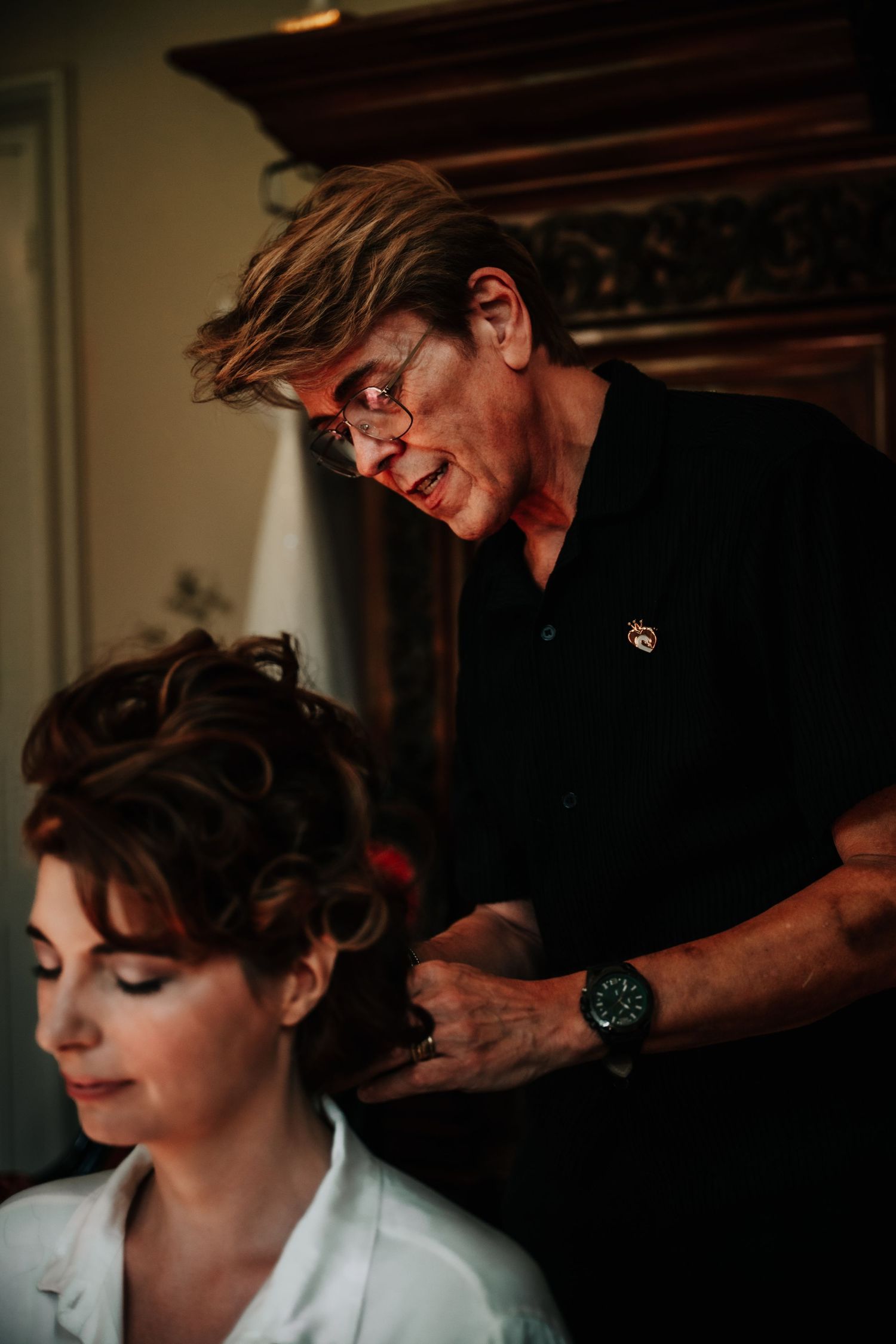Behind-the-scenes preparation moment showing styling of dark curled hair.