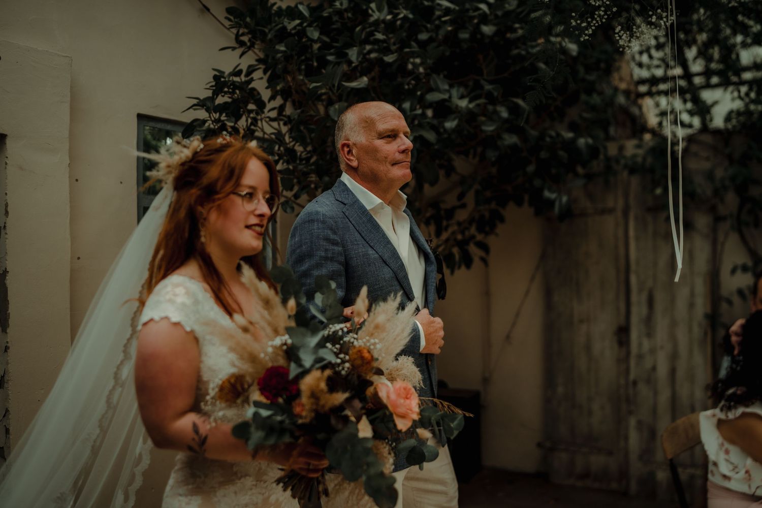 Wedding ceremony processional in a charming garden courtyard with natural lighting.