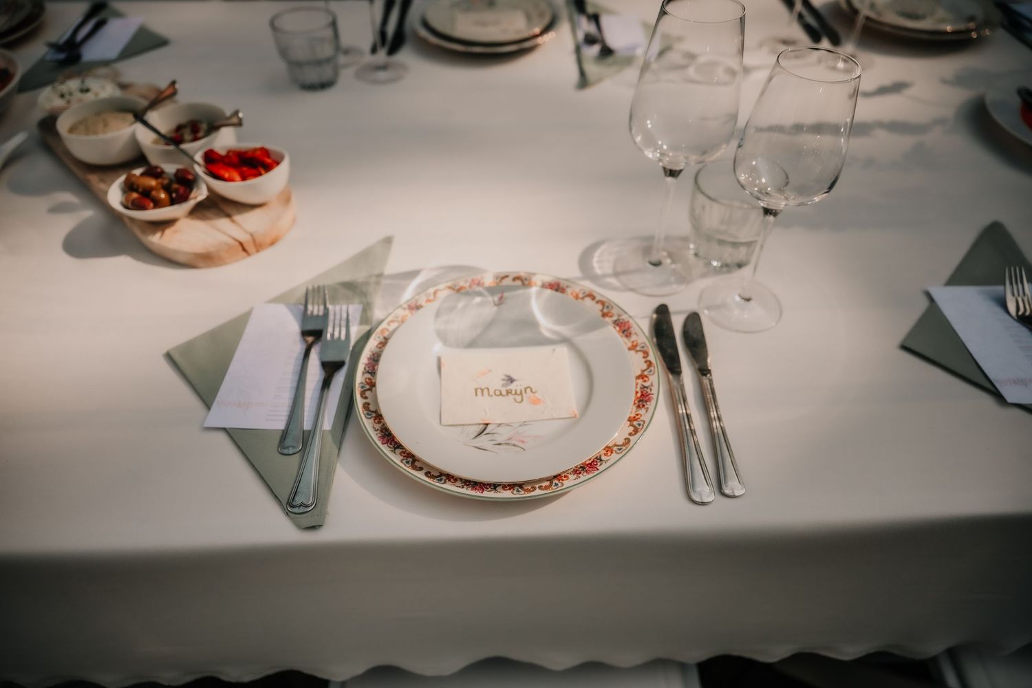 Formal place setting at a wedding reception with white linens and glassware.
