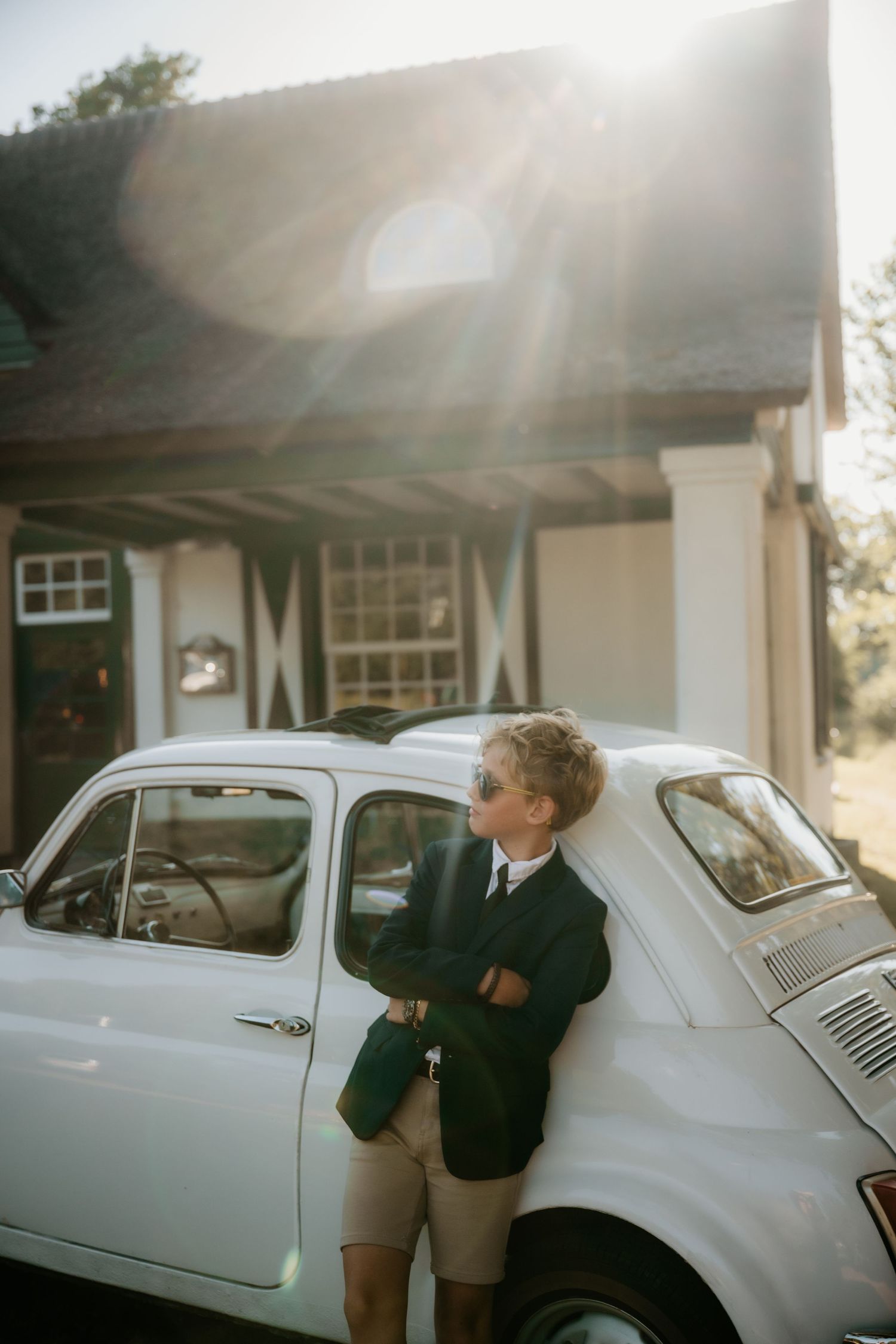 A classic white vintage car parked outside a house on a sunny day.