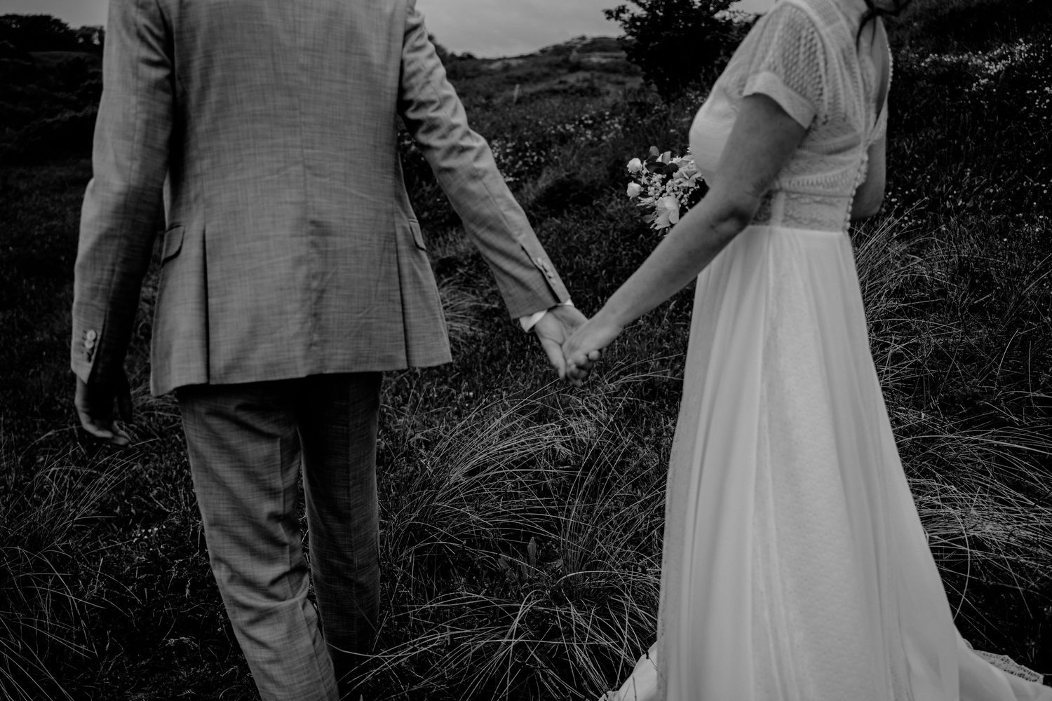 Black and white wedding photos showing intimate moments between a couple on a grassy hillside.