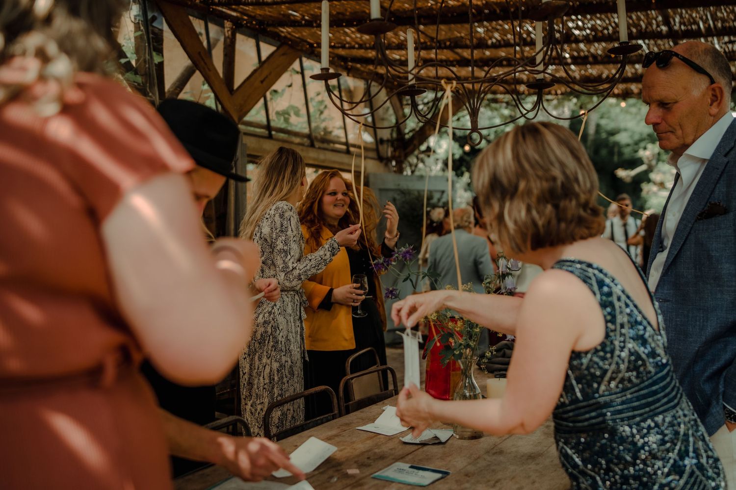 Wedding guests gathered under a rustic wooden pavilion during a reception celebration.