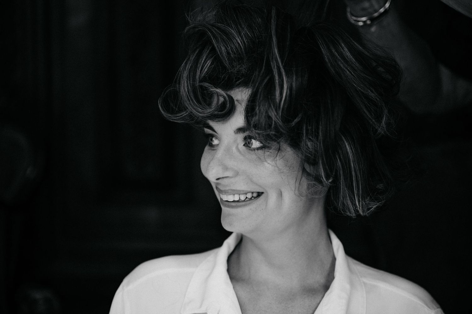 A black and white portrait photo showing a person smiling and wearing dark sunglasses.