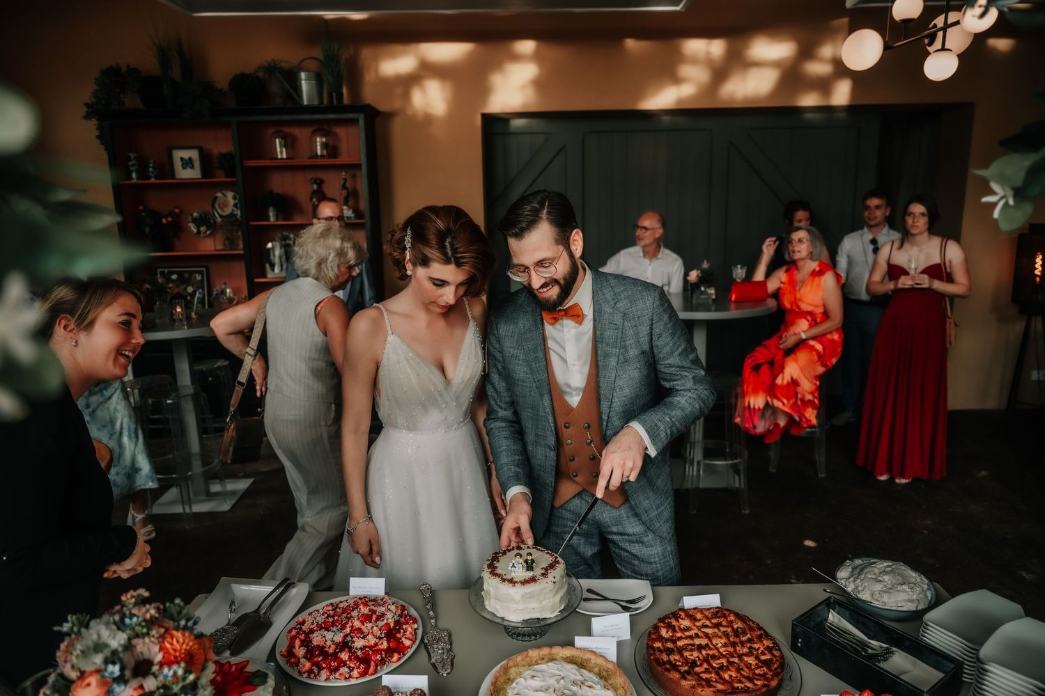 Wedding reception venue with festive lighting and guests celebrating at decorated tables.
