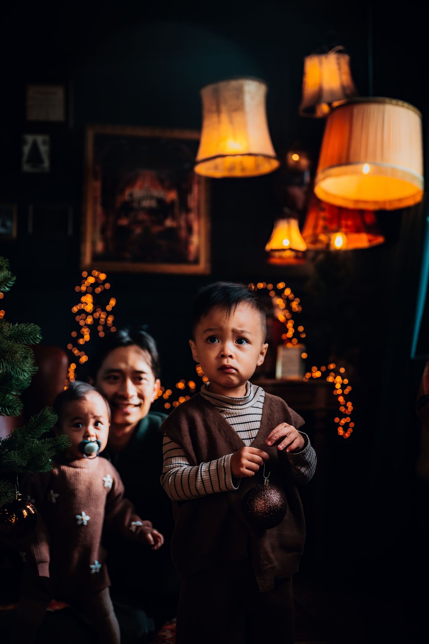 A series of moody indoor photographs showing children in dim lighting with warm glowing lamps and string lights in the background.