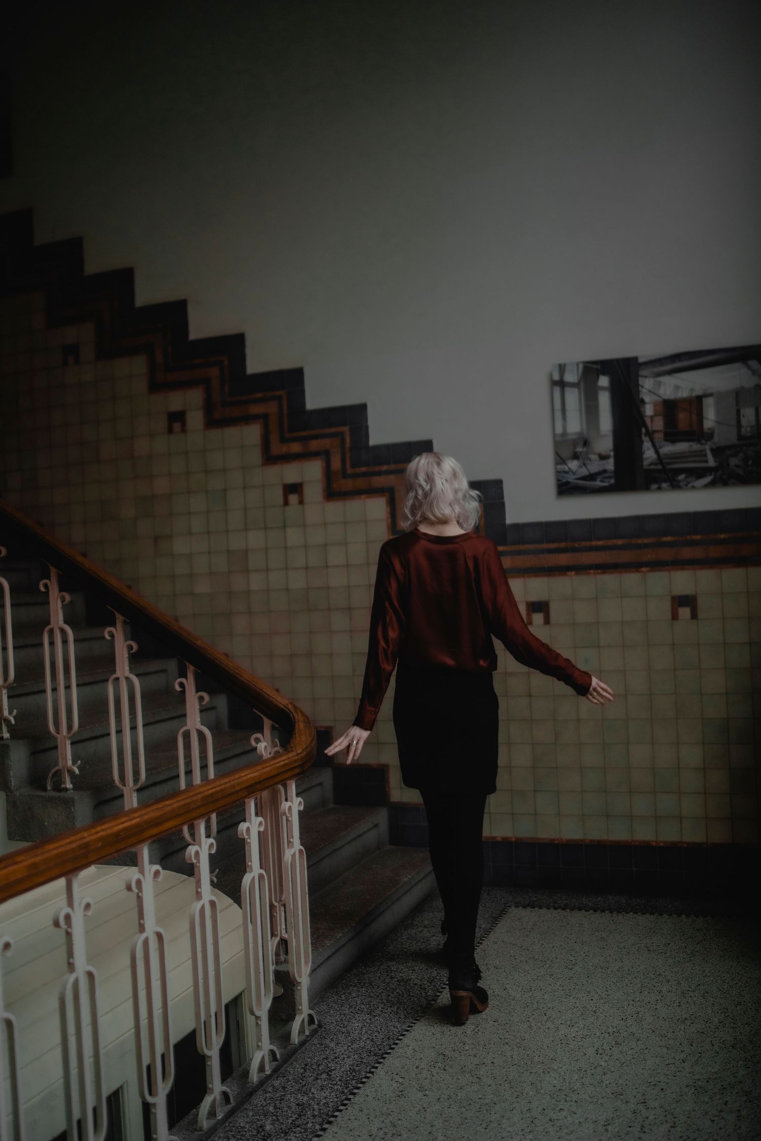 A sequence of photos showing someone walking up dimly lit stairs with a wooden handrail in an institutional setting.