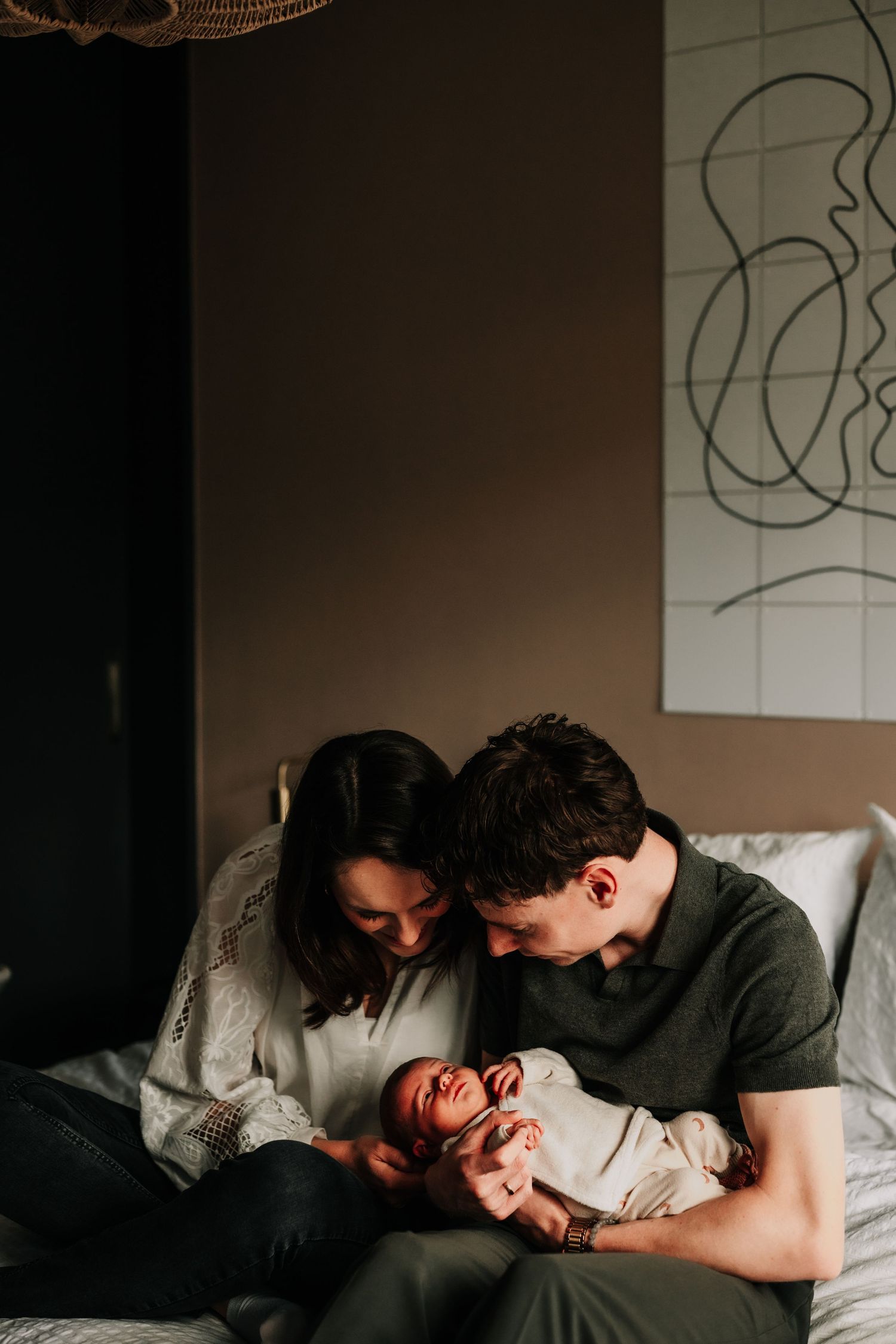 A tender moment shared between family members on a bed with abstract wall art.