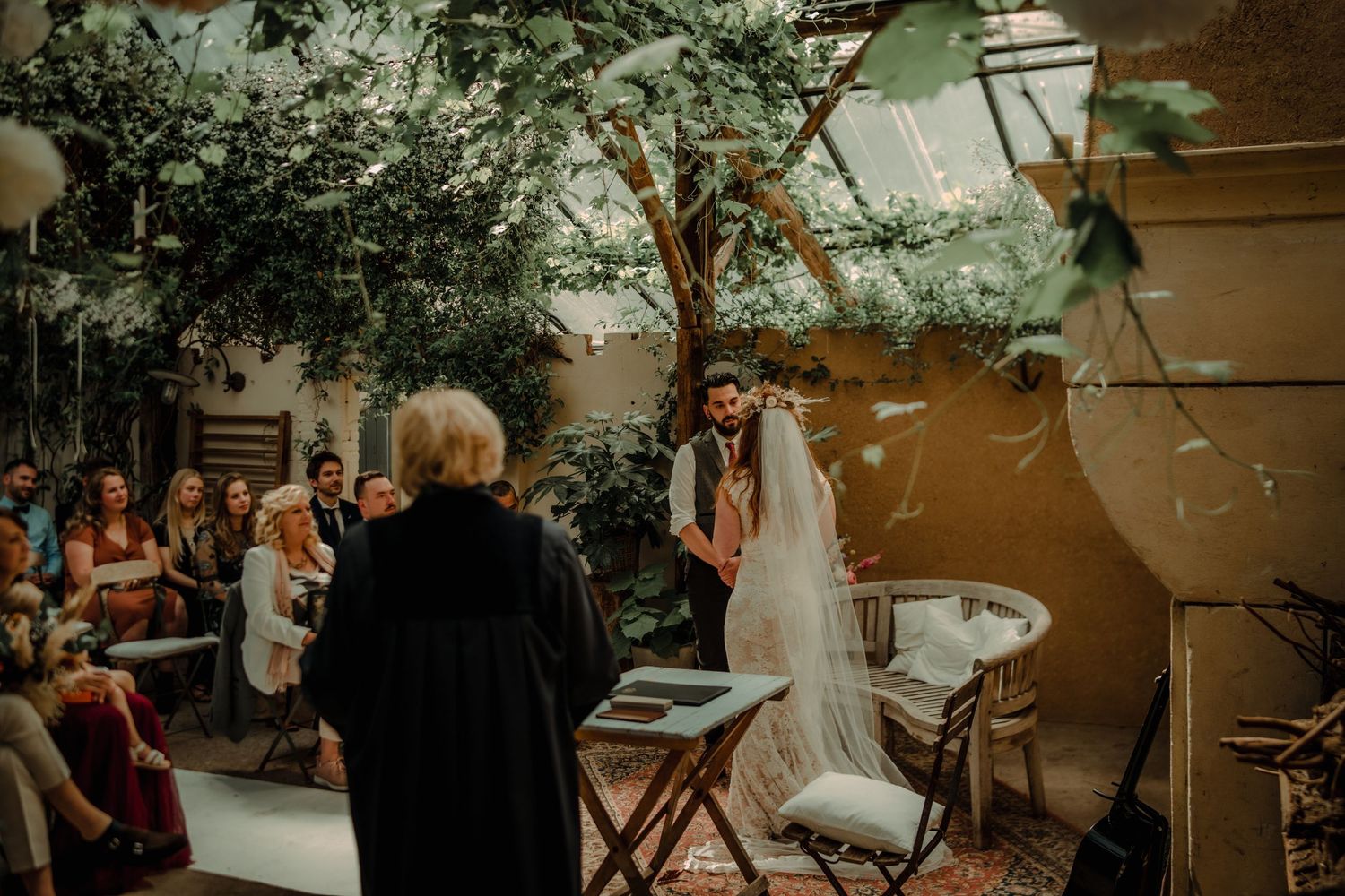Wedding ceremony in a lush garden courtyard with string lights and natural decor.