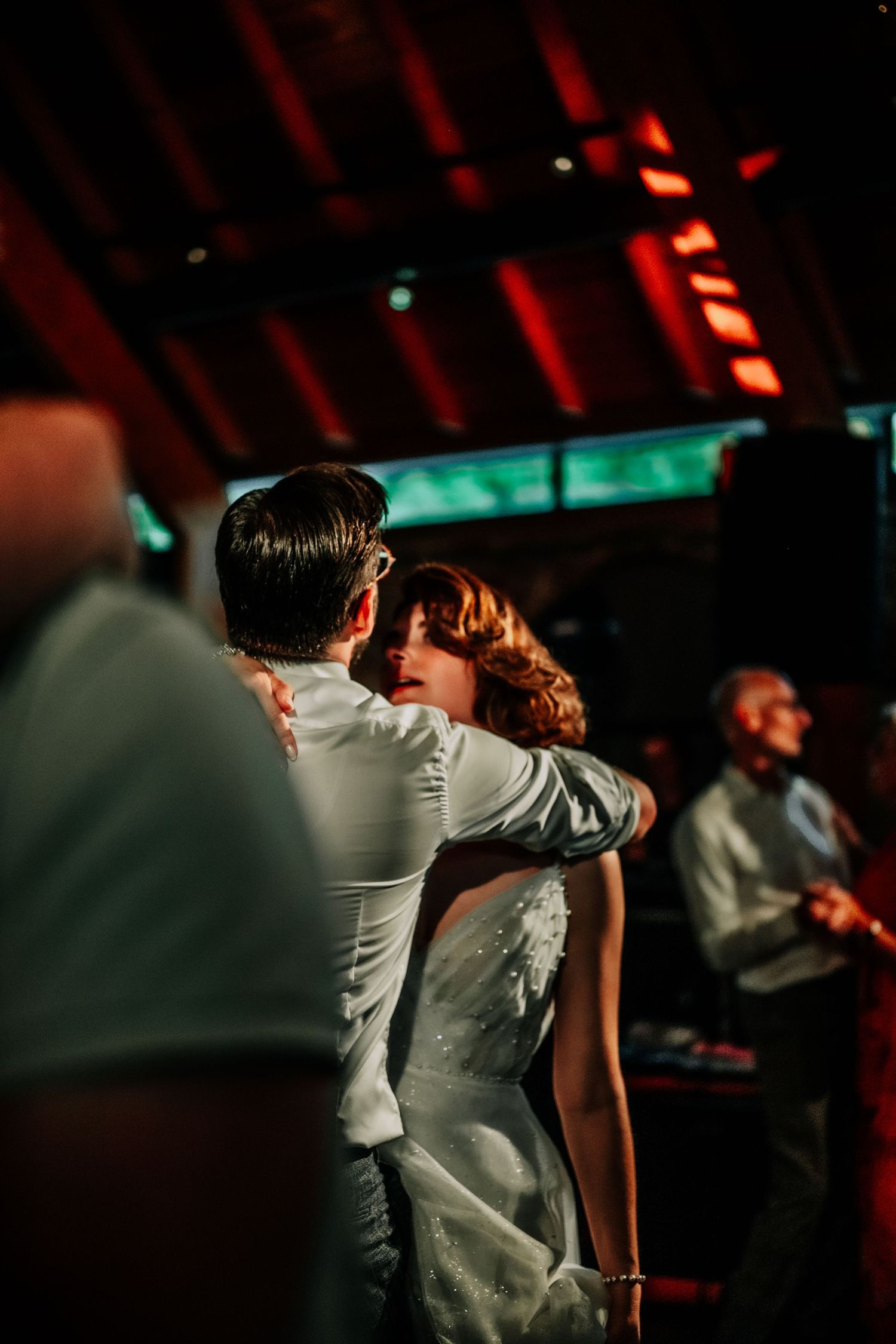 Wedding guests dancing under dramatic red lighting at an evening reception.