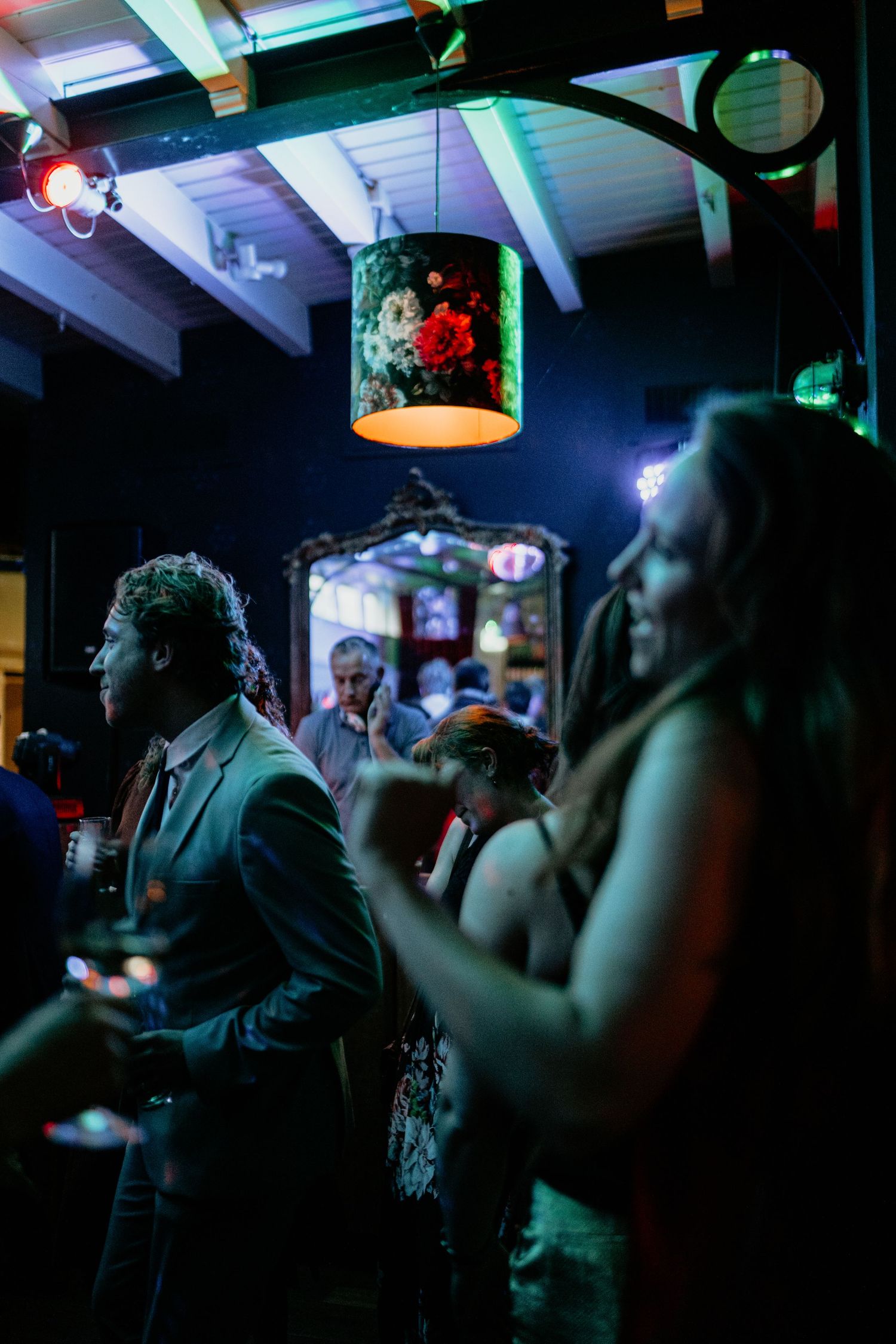 Party guests dancing in a dimly lit venue with colorful ambient lighting and decorations.