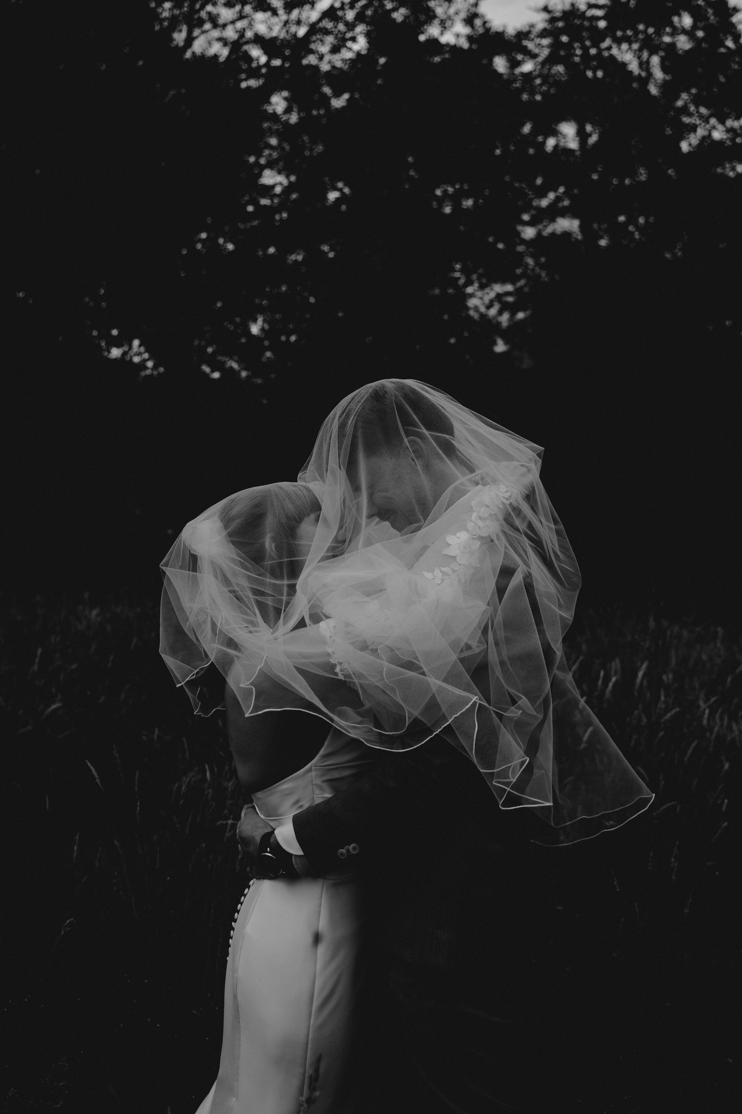 Artistic black and white photo of flowing bridal veil against dark background.