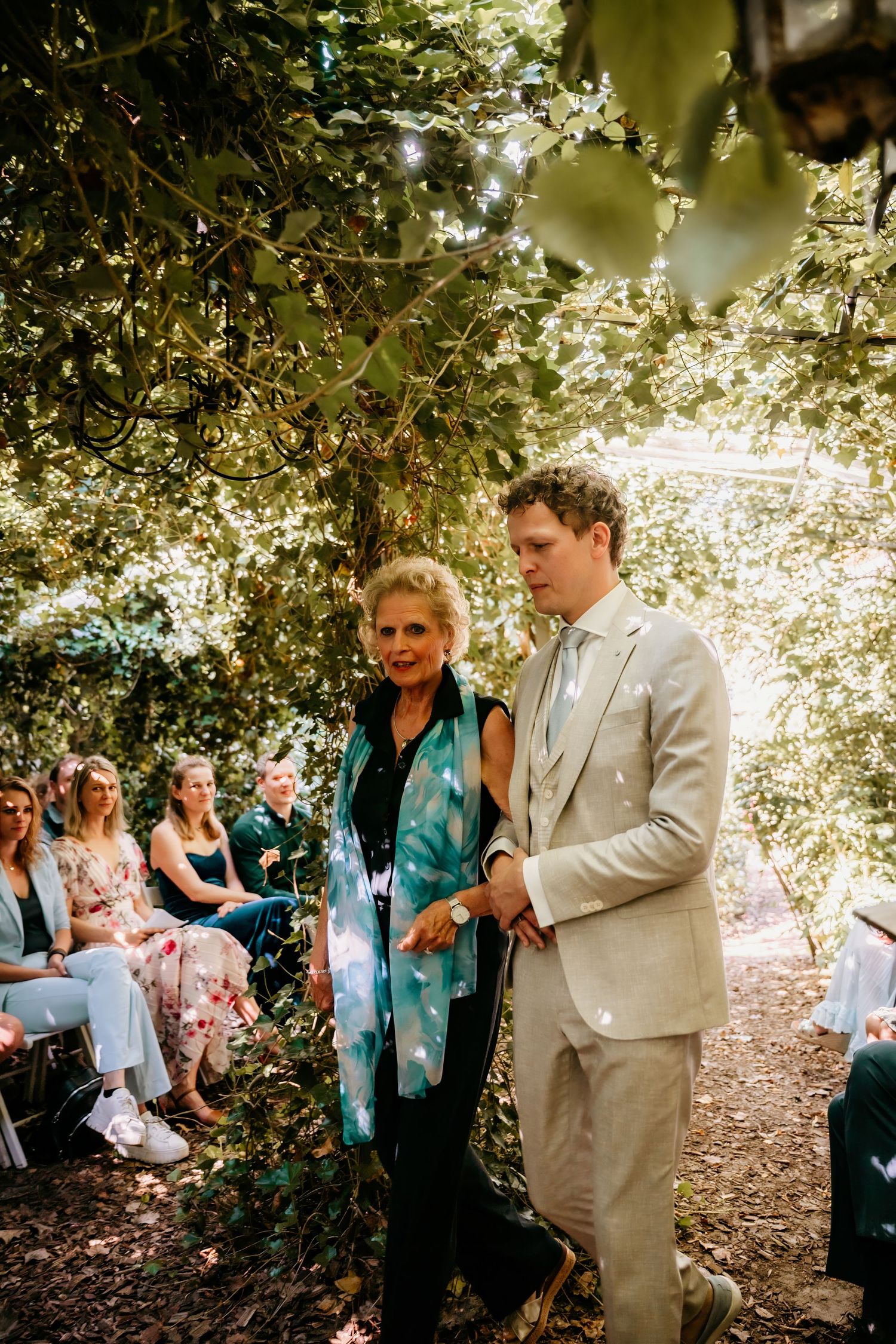 Wedding ceremony taking place in a serene wooded setting with guests seated among the trees.