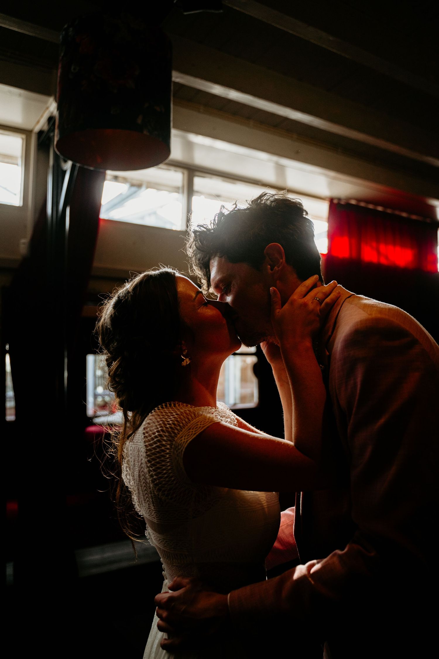 Silhouetted couple shares an intimate moment in a dimly lit indoor space.