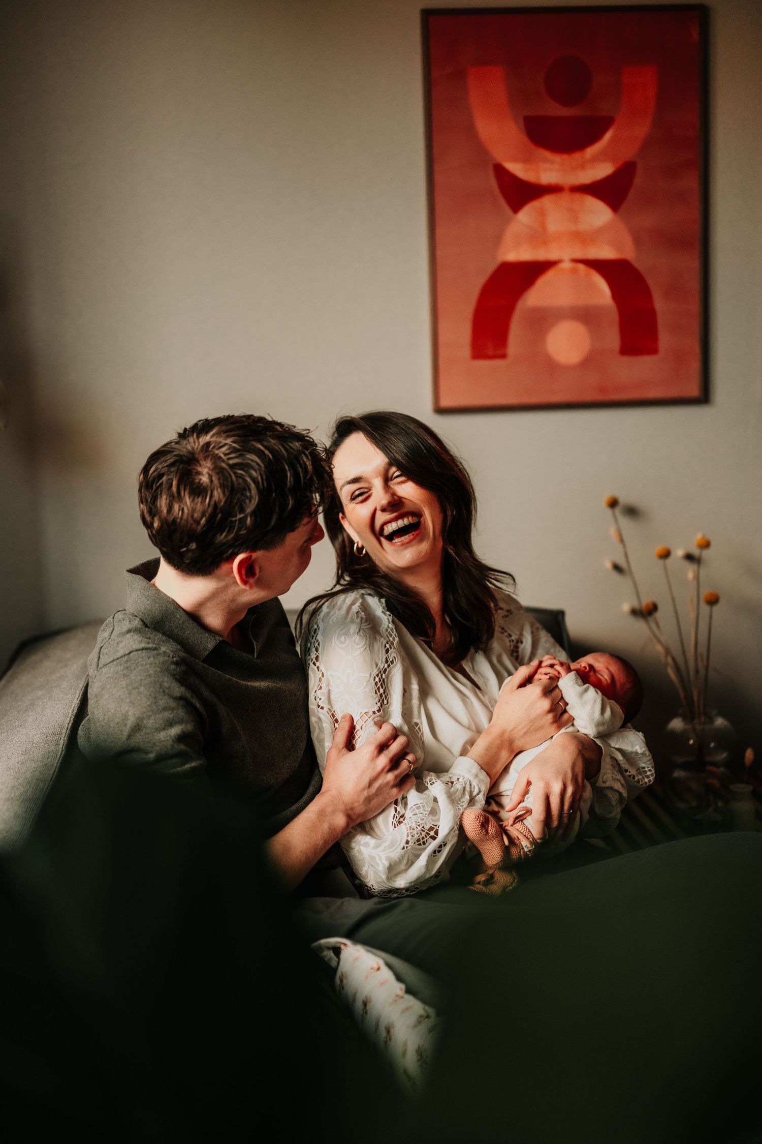A tender family moment on a couch with abstract red artwork on the wall.