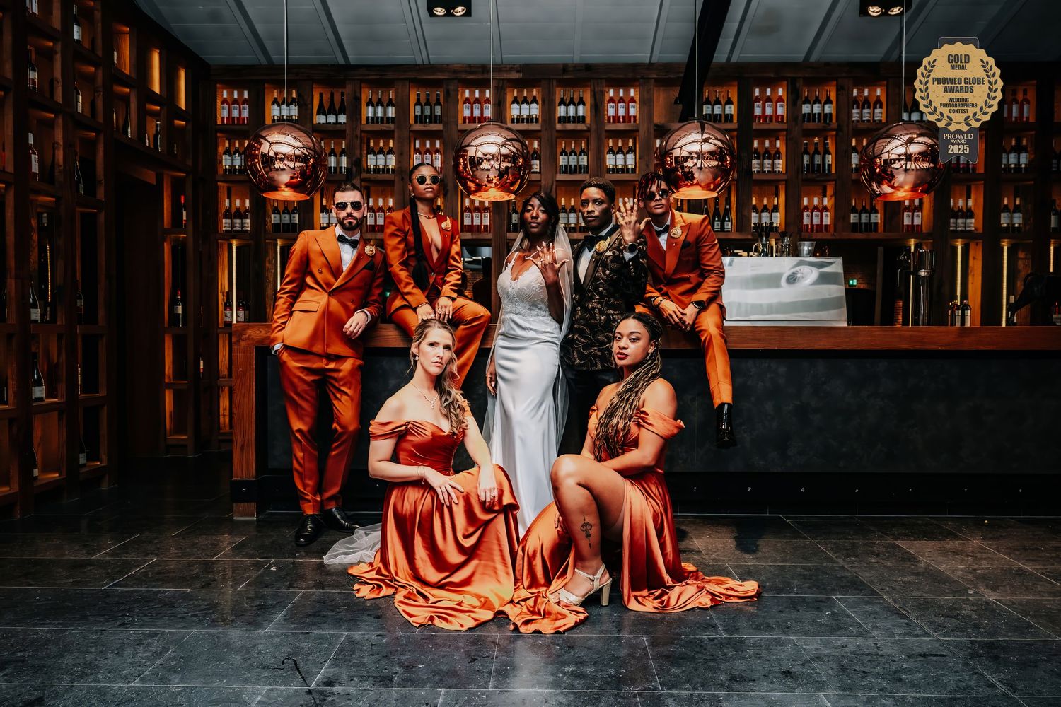 Group of dancers in vibrant orange flamenco dresses perform in a dimly lit venue during a traditional Spanish dance show.
