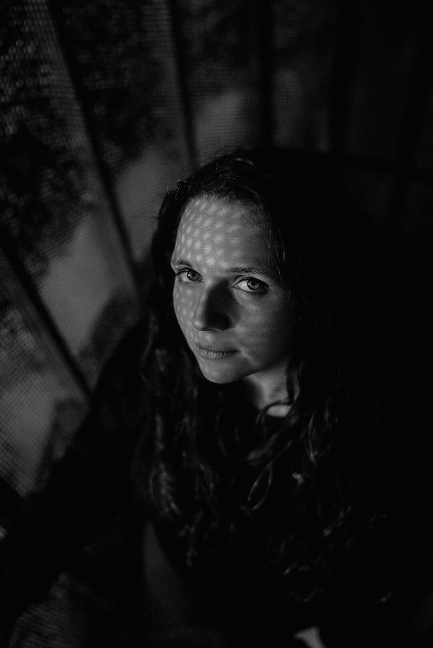 Dramatic black and white portrait with moody lighting and shadows creating an atmospheric composition.